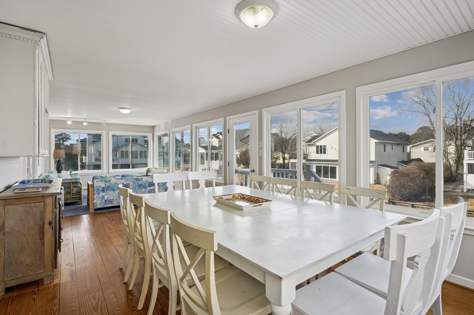 Gather around this spacious dining table with seating for ten, where floor-to-ceiling windows bathe the room in natural light and frame neighborhood views that make every meal feel special.