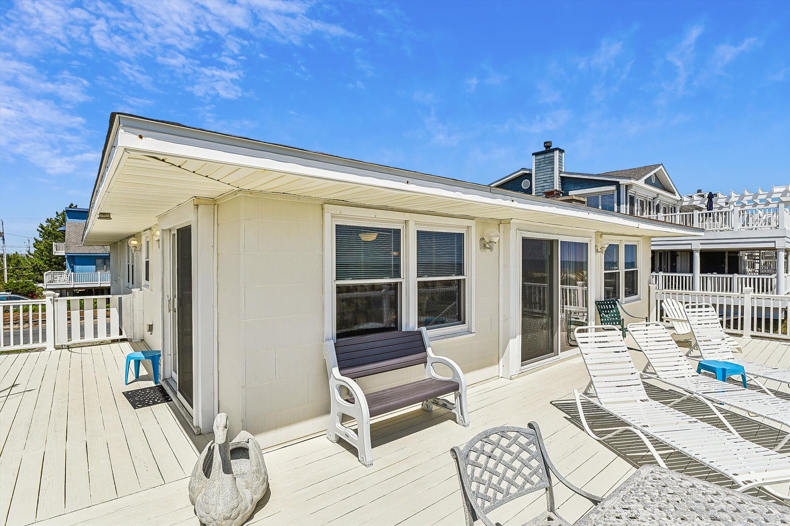 Sun-drenched deck surrounds a charming beach cottage in a quiet coastal neighborhood, offering easy access to nearby shores and local attractions.