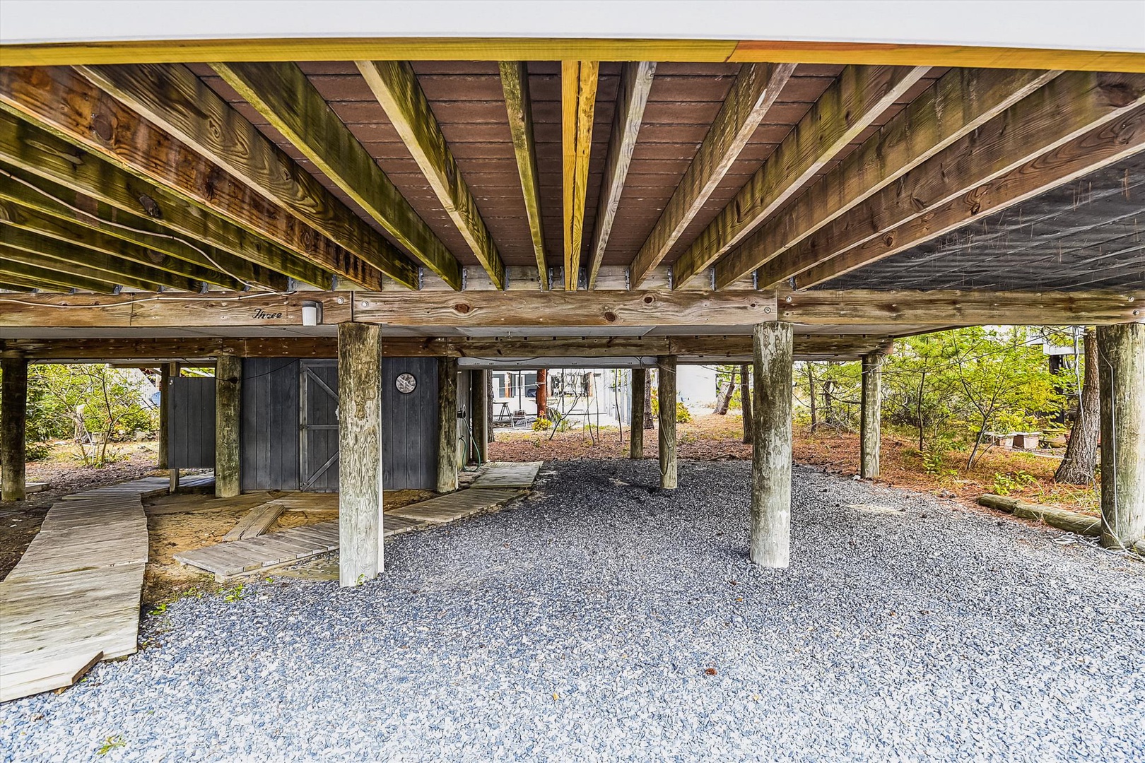 Covered parking beneath the property provides convenient shelter for your vehicle with rustic wooden beams overhead and easy access to your vacation retreat.