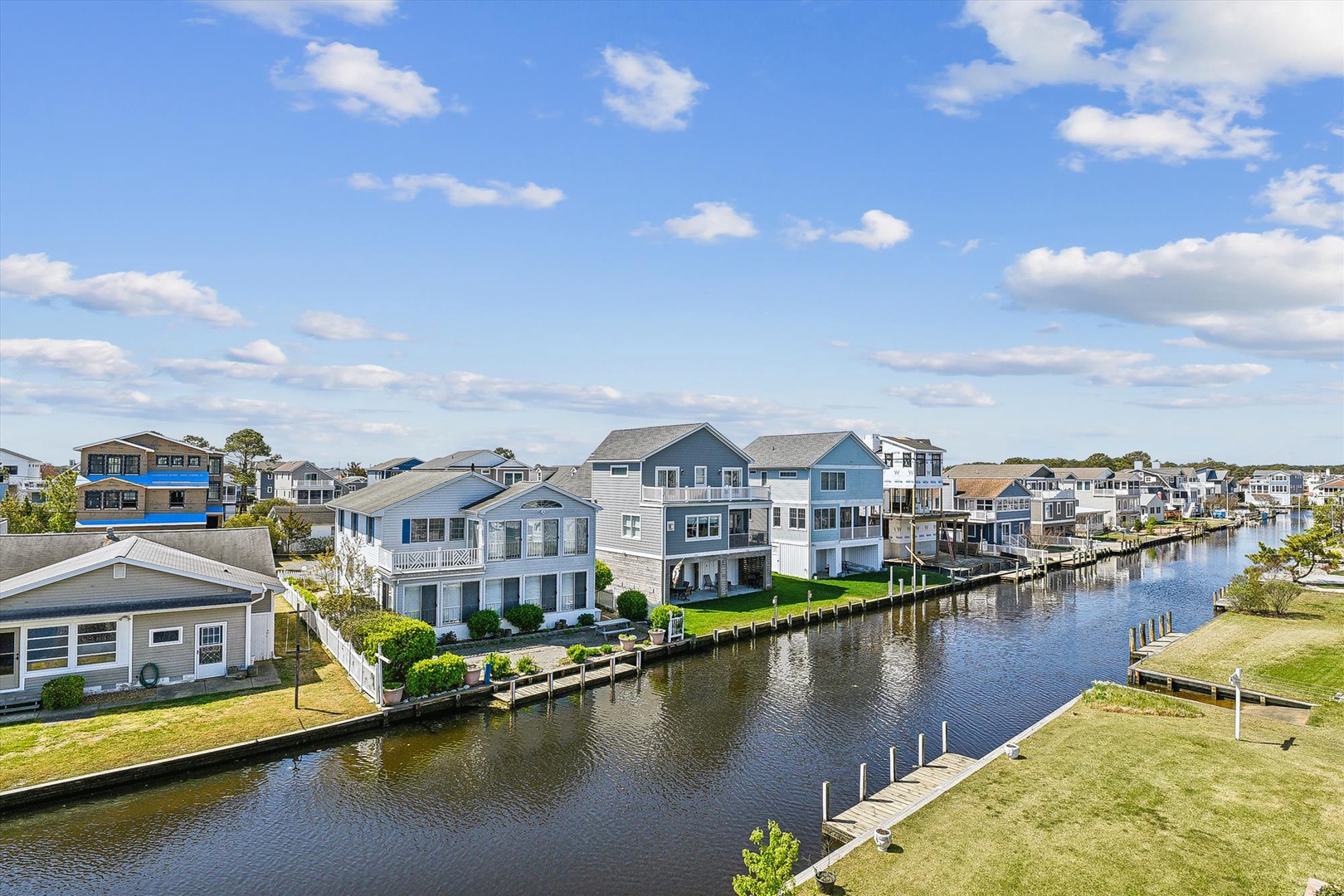 Aerial view of a peaceful waterfront neighborhood with canal access, boat docks, and coastal homes nestled along scenic waterways.