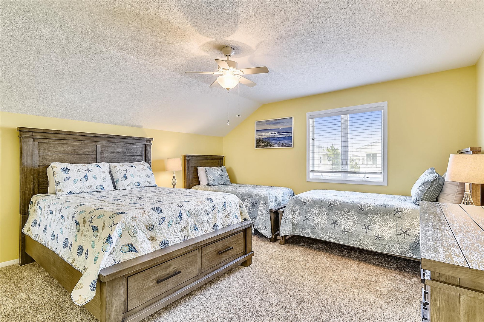 Your bright, spacious bedroom offers a restful retreat with comfortable beds dressed in coastal-inspired linens, warm natural light, and a gentle ceiling fan to keep you cool.
