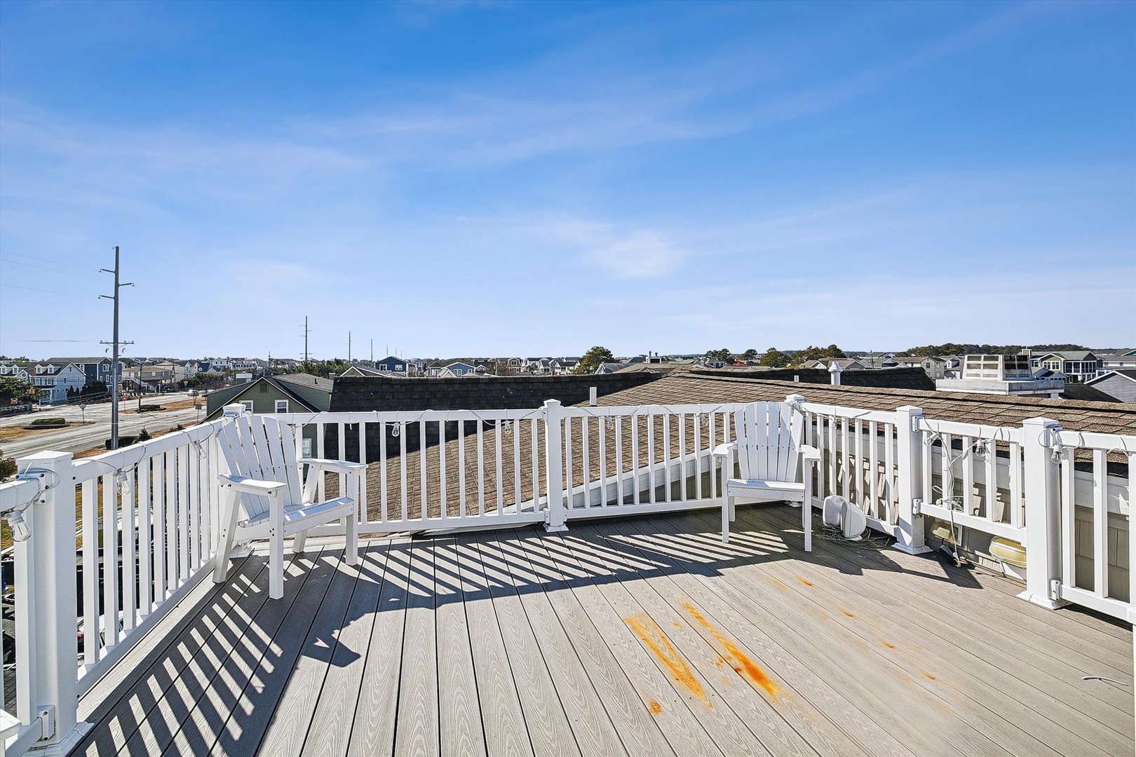 Spacious rooftop deck with panoramic neighborhood views, featuring comfortable seating and bright blue skies overhead.