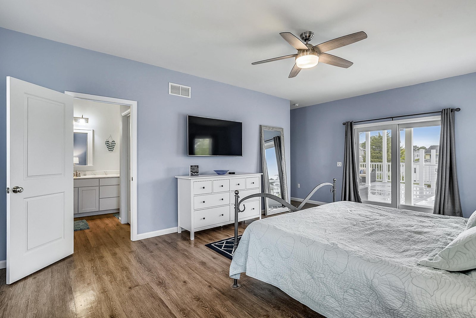 Sink into the plush bed in this serene blue bedroom, where your private balcony awaits and the ceiling fan keeps you cool and comfortable.