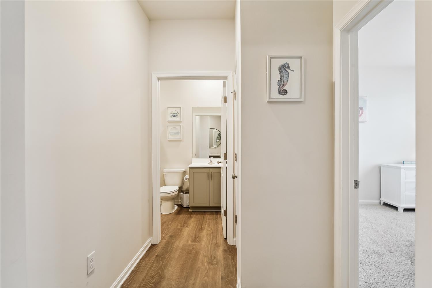 The hallway connects your private spaces with soft coastal touches—seahorse art adds charm as you move between bedroom and bath.
