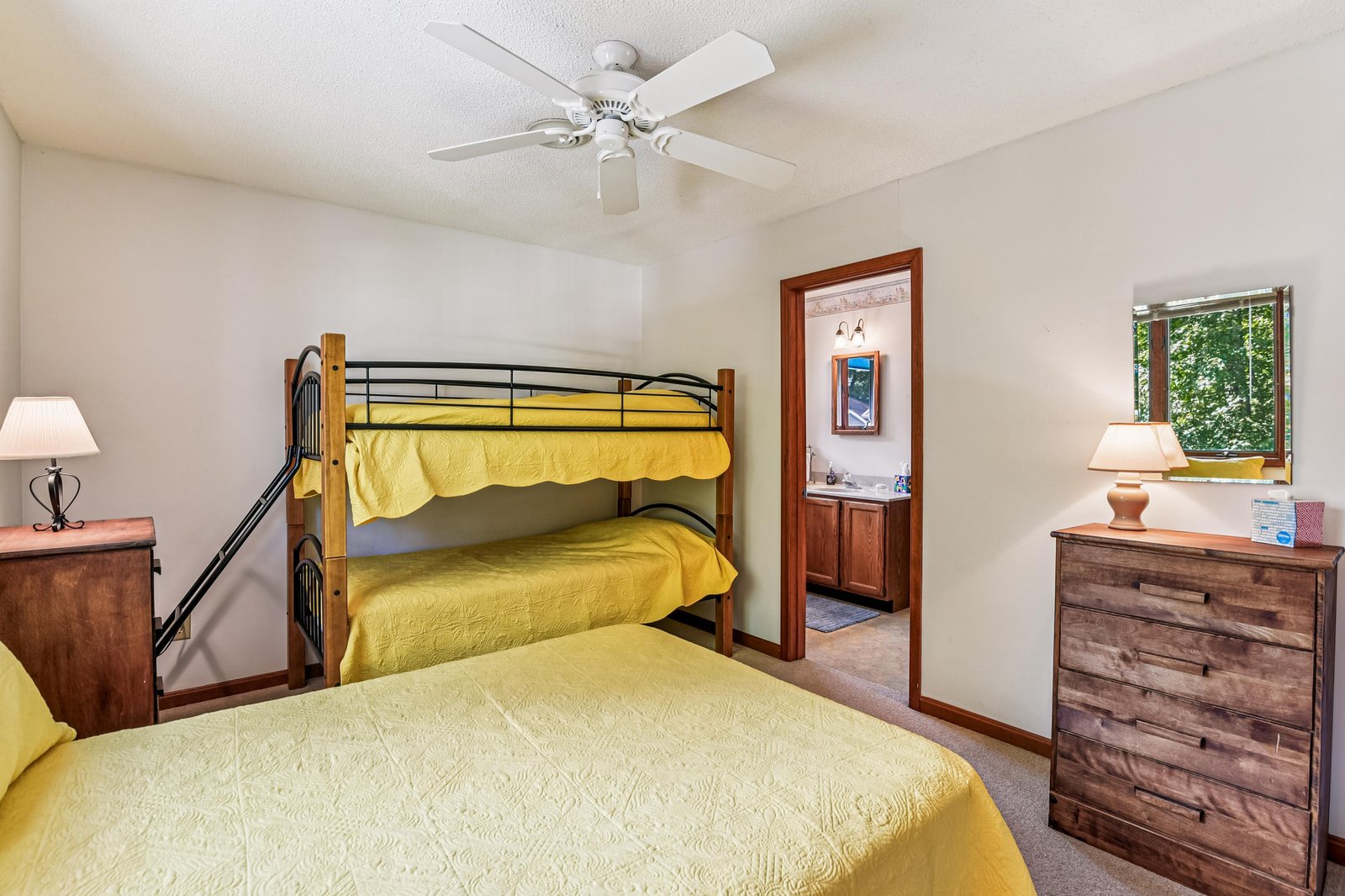 Your family-friendly bedroom sleeps up to five with a cozy queen bed and sturdy bunk beds, all dressed in cheerful yellow linens that catch the natural light streaming through the window.