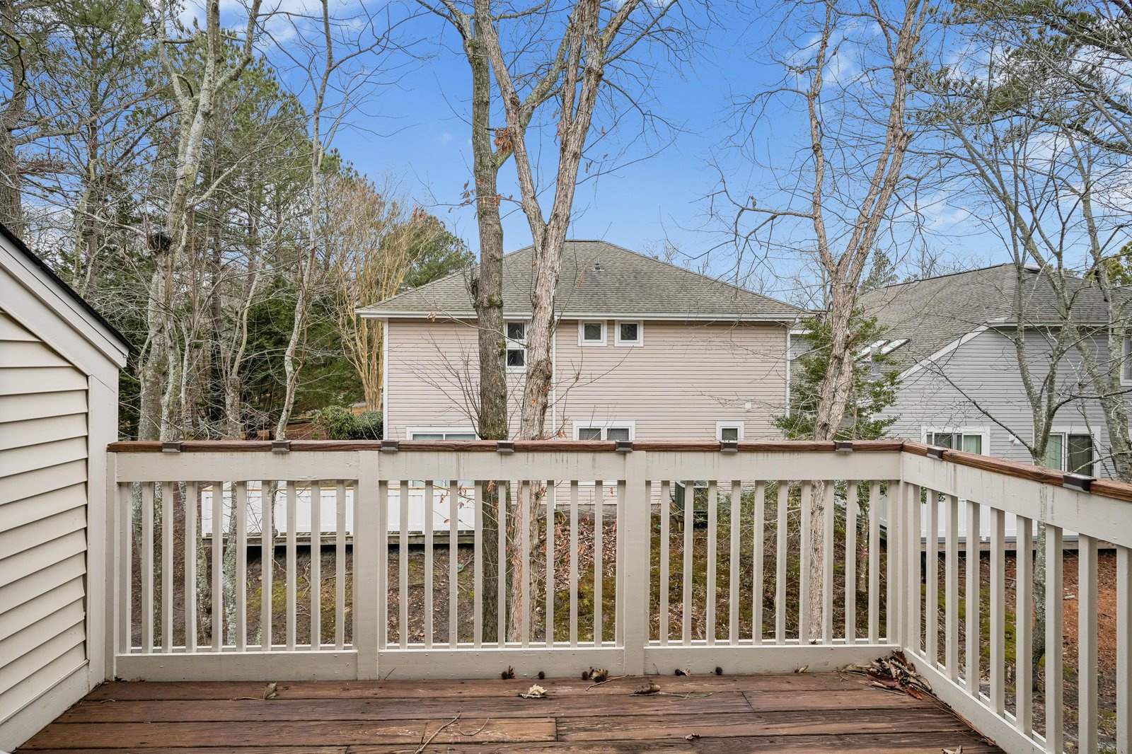 An outdoor wooden deck overlooks neighboring properties and a wooded residential area, offering a quiet outdoor space within a peaceful community setting.