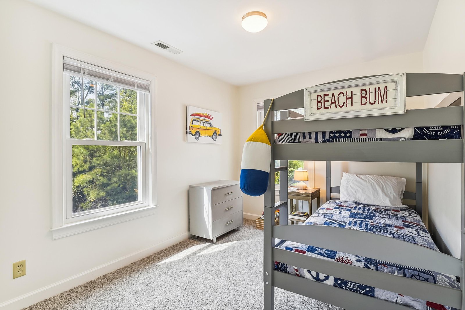 Wake up to a fresh beach vibe in your cozy bunk room. Kids will love the nautical theme, soft linens, and leafy treetop views through the bright windows—perfect for family getaways.