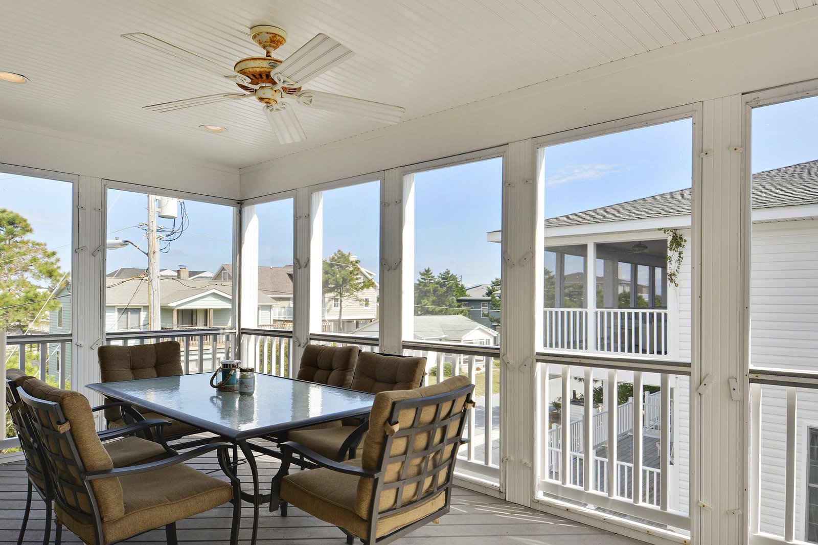 Enjoy your morning coffee in this bright screened porch, where the gentle ceiling fan keeps you cool while you take in peaceful views of the surrounding neighborhood.