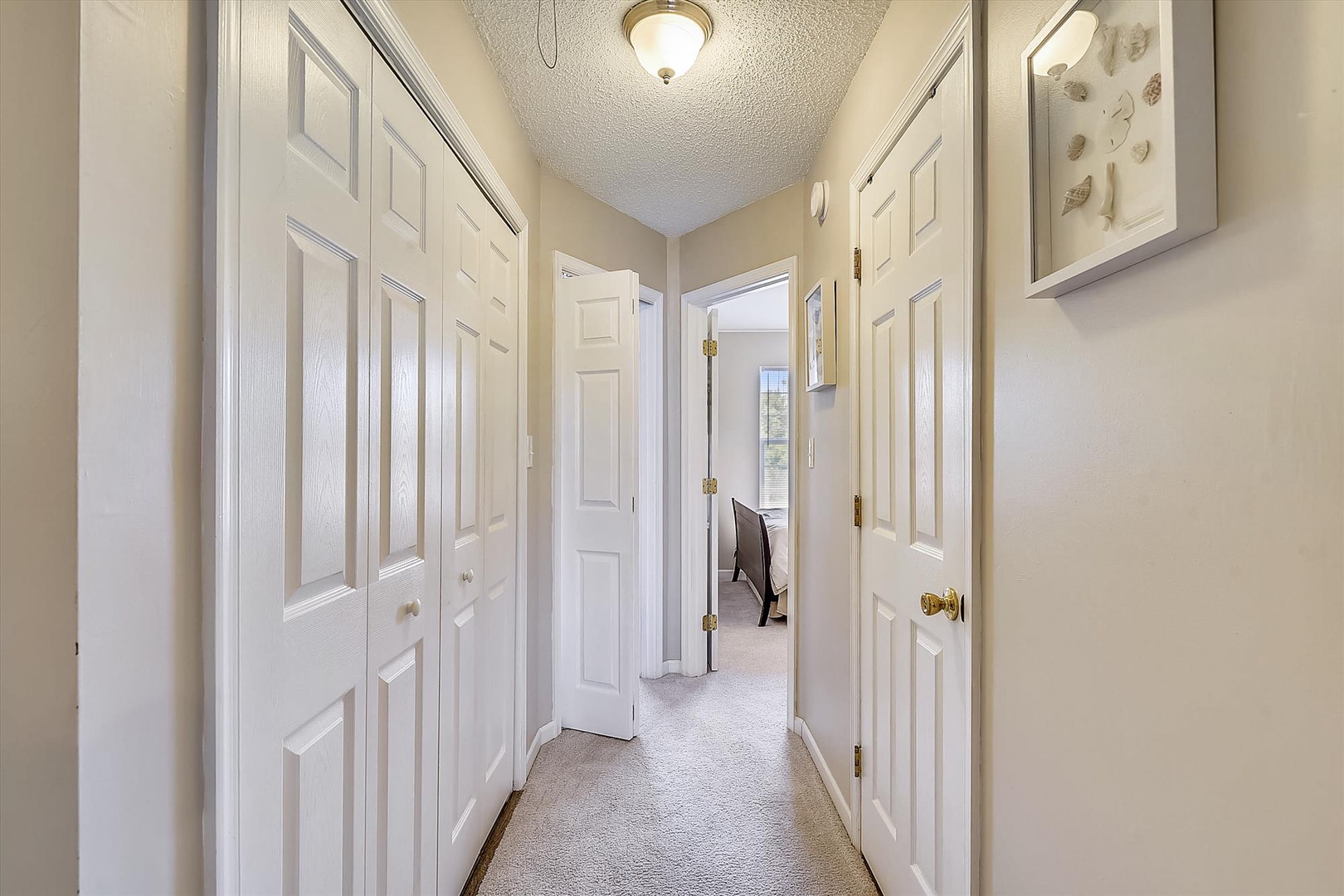 A bright hallway with abundant storage behind classic white doors leads you to the peaceful sleeping quarters, offering convenient access to all your vacation essentials.