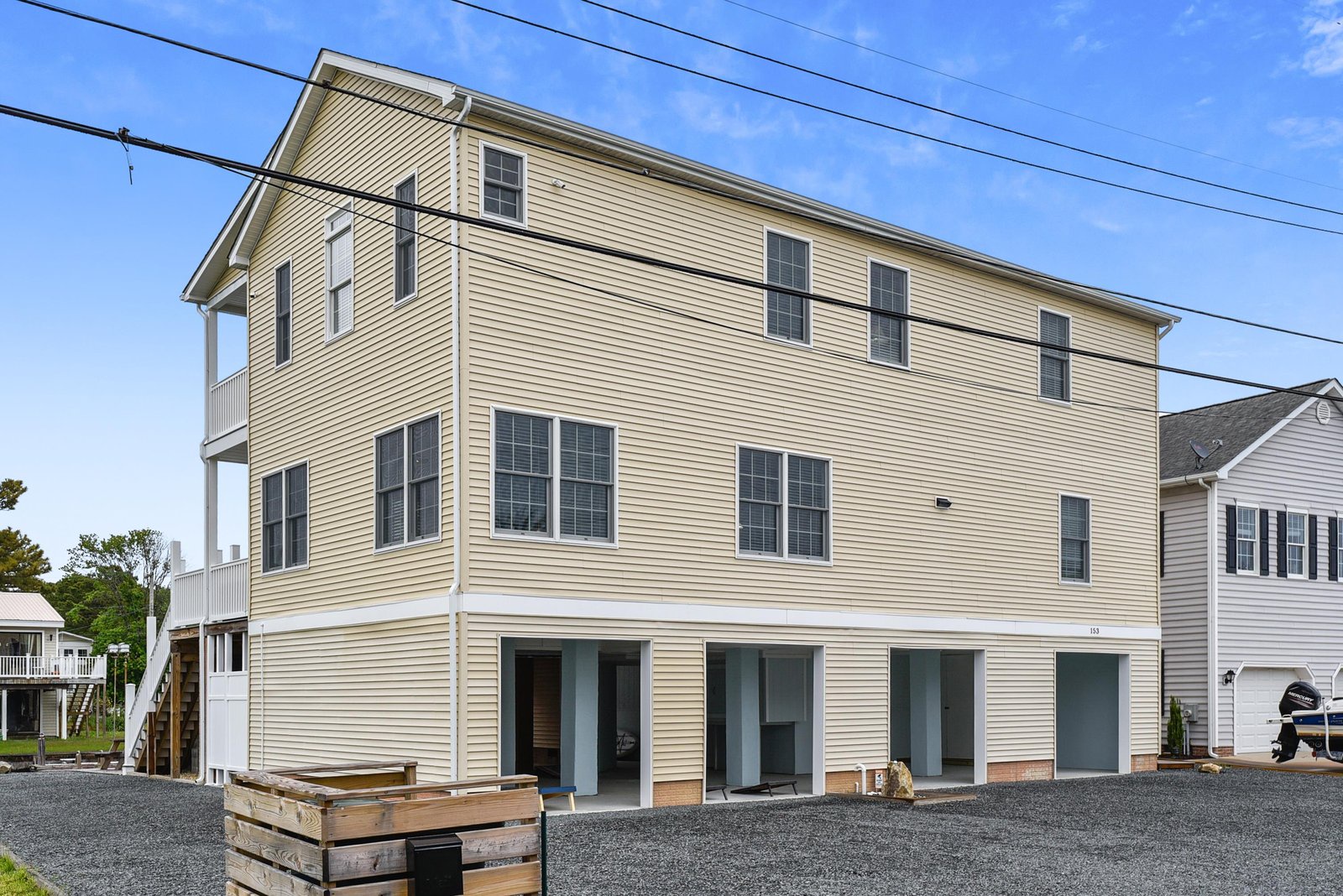 A spacious beachside property featuring modern construction with two upper floors of accommodations and a ground-level parking area with ample space for guests.