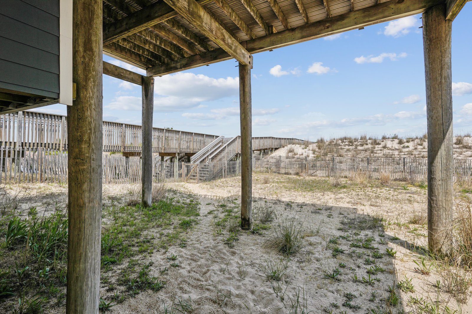 A covered walkway frames a path through the dunes, offering sheltered beach access just steps from the property.