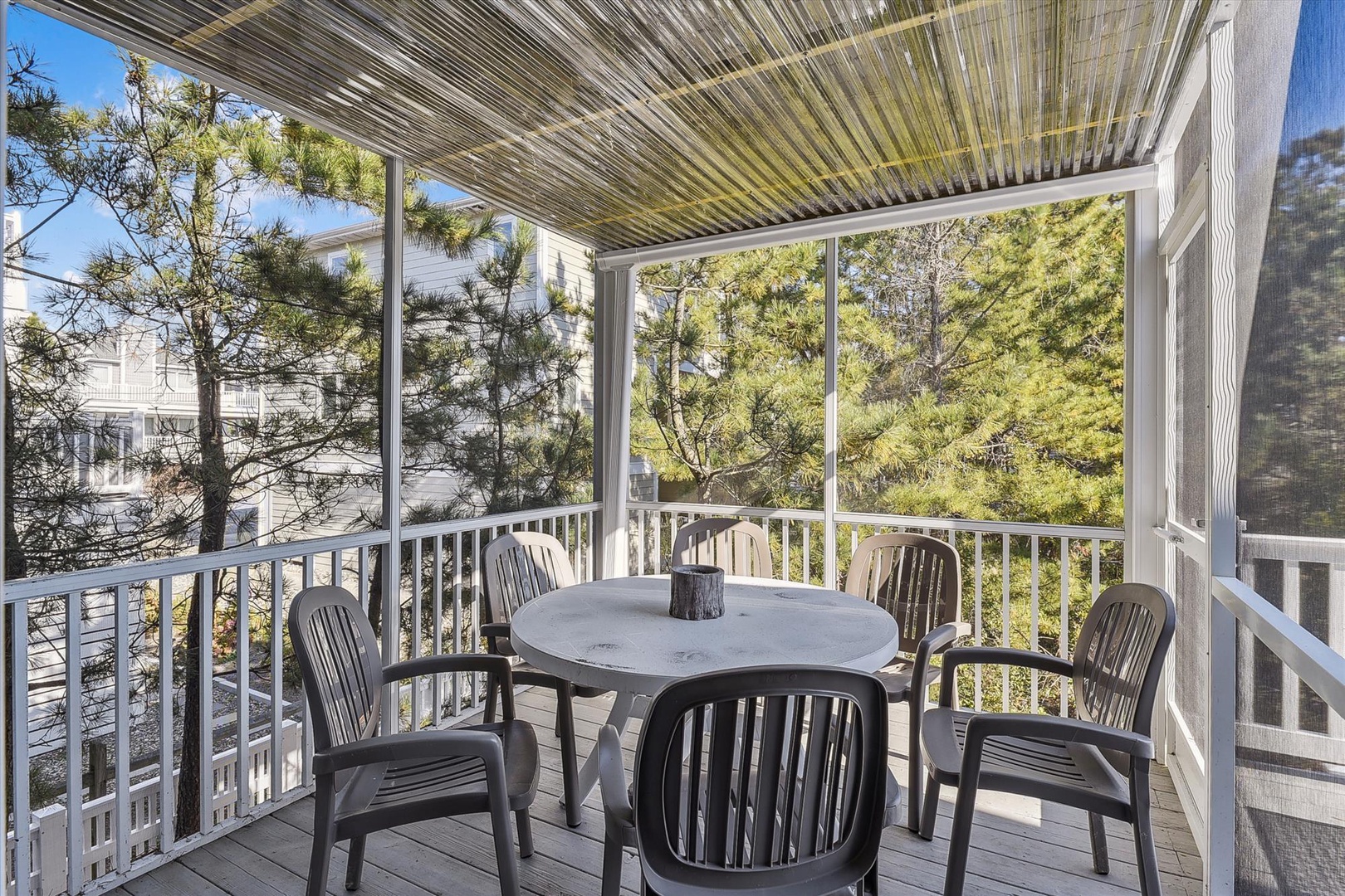 Sip your morning coffee on this screened porch, where a round table for five invites quiet conversation surrounded by lush greenery and filtered sunlight.