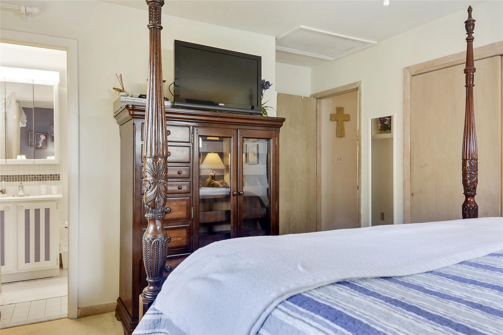 Unwind in your beautifully appointed bedroom featuring a handcrafted four-poster bed, elegant antique armoire with entertainment center, and pristine ensuite bathroom just steps away.