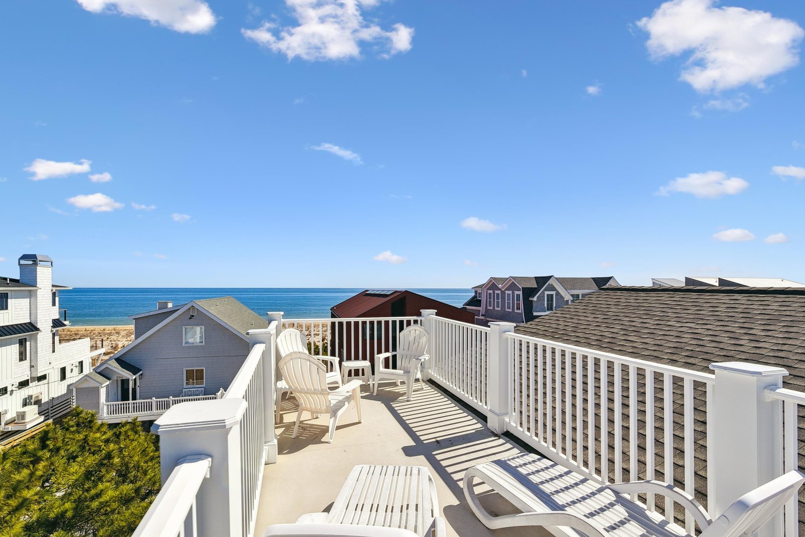 A sunny rooftop deck with comfortable seating and sweeping coastal views. Bright blue skies and sparkling water set the scene for relaxed seaside mornings and sunset evenings.