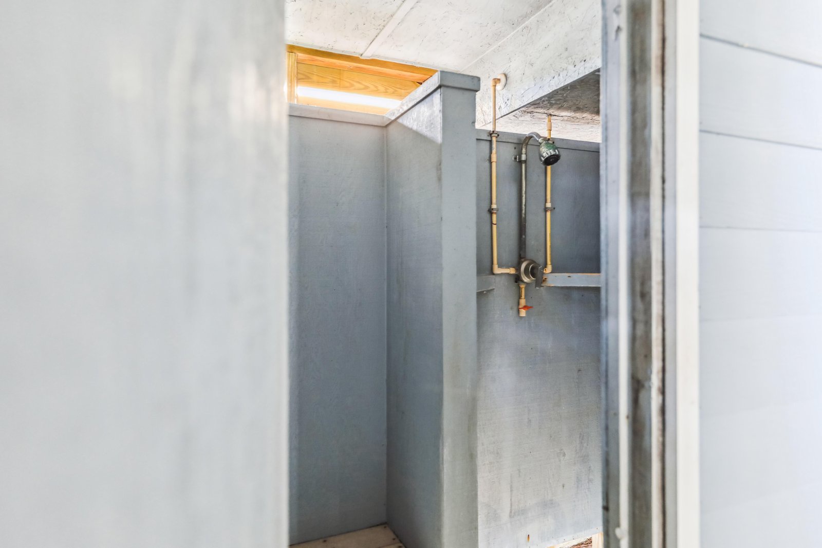 Modern industrial-style shower with exposed copper piping and a skylight above, bringing natural light into your private retreat.