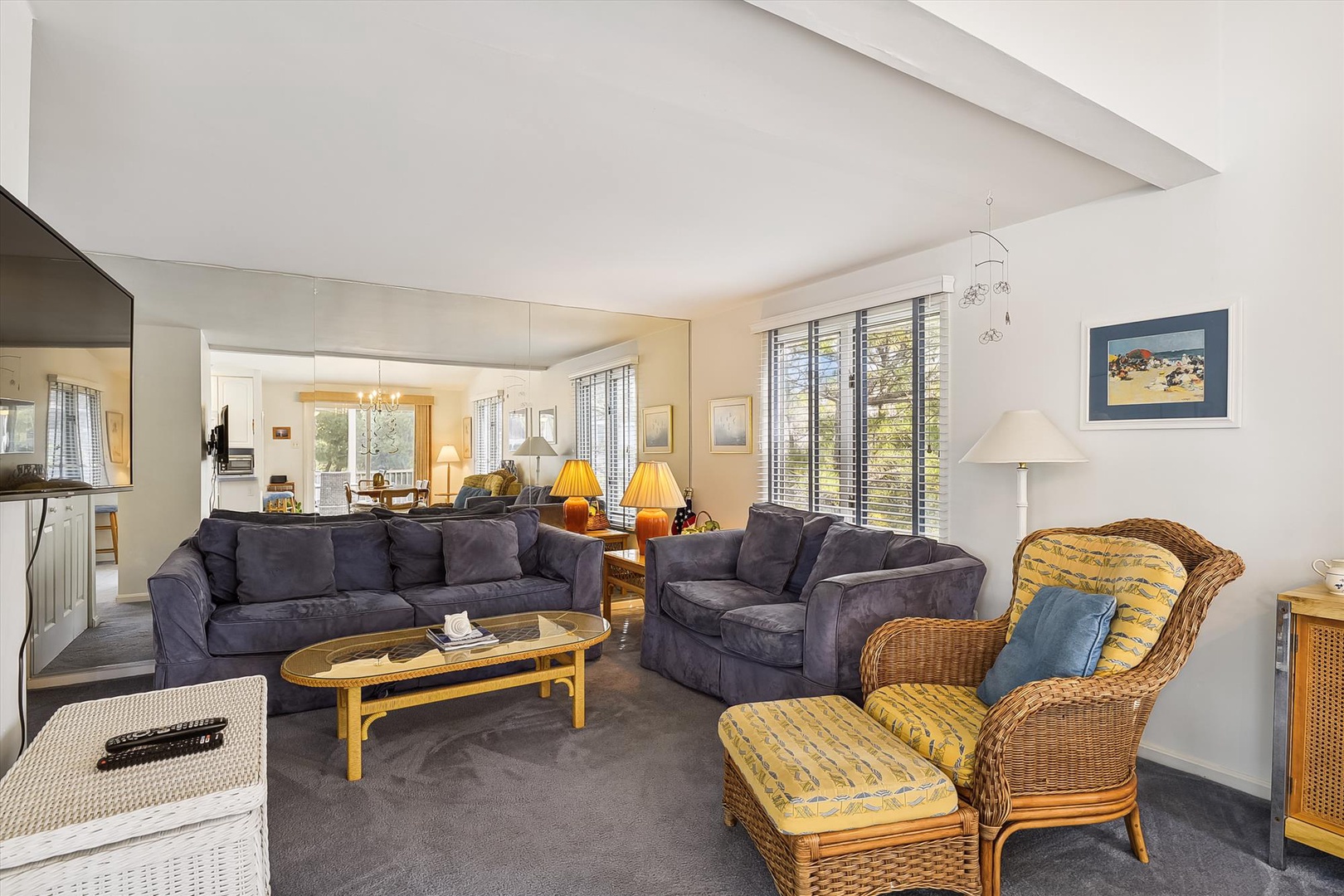 Sink into plush sofas and wicker chairs in your spacious living room, where natural light pours through large windows and a stylish skylight overhead creates an airy, inviting retreat.