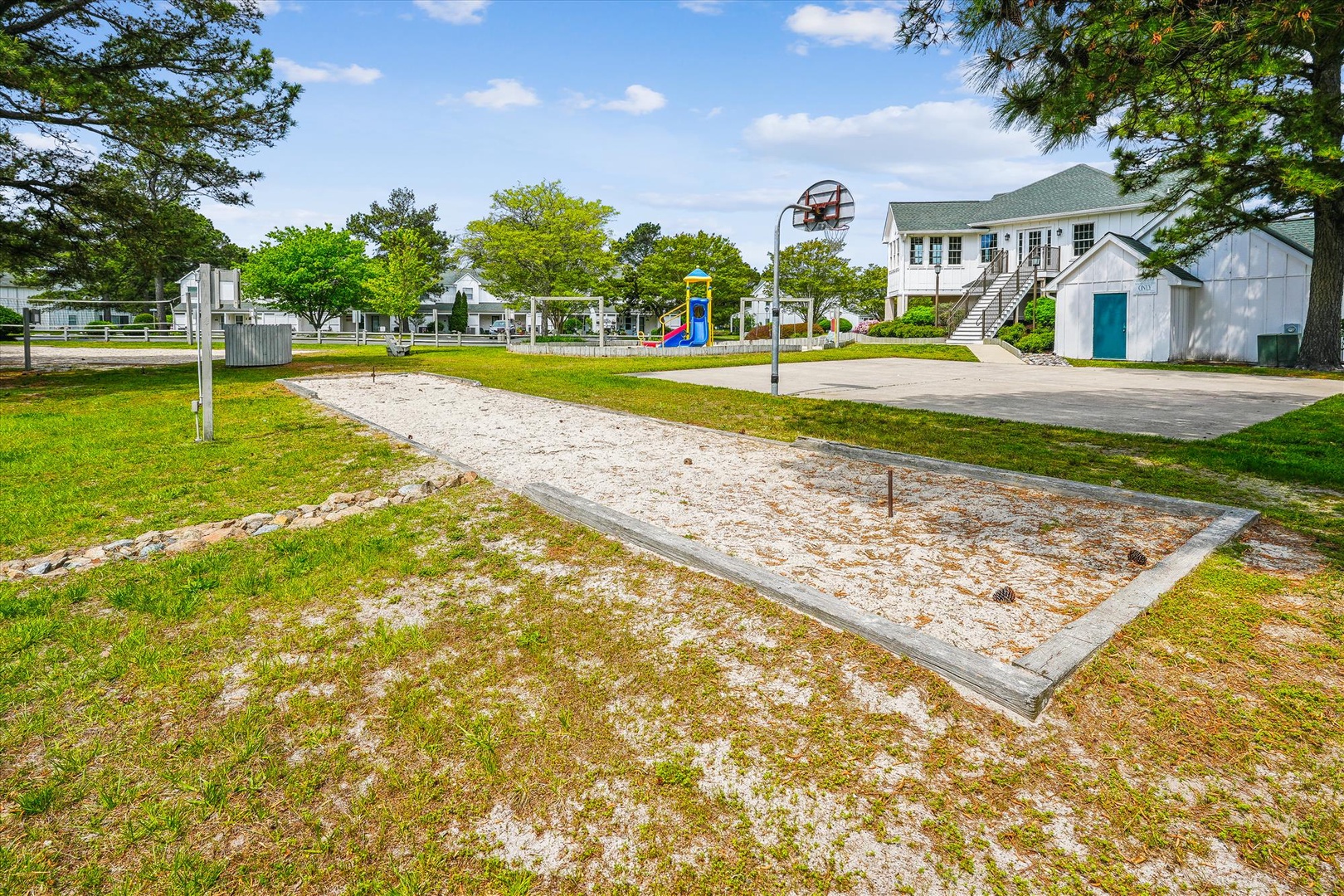 Community recreational area features a horseshoe pit, basketball court, playground, and surrounding green spaces—ideal for outdoor activities during your stay.