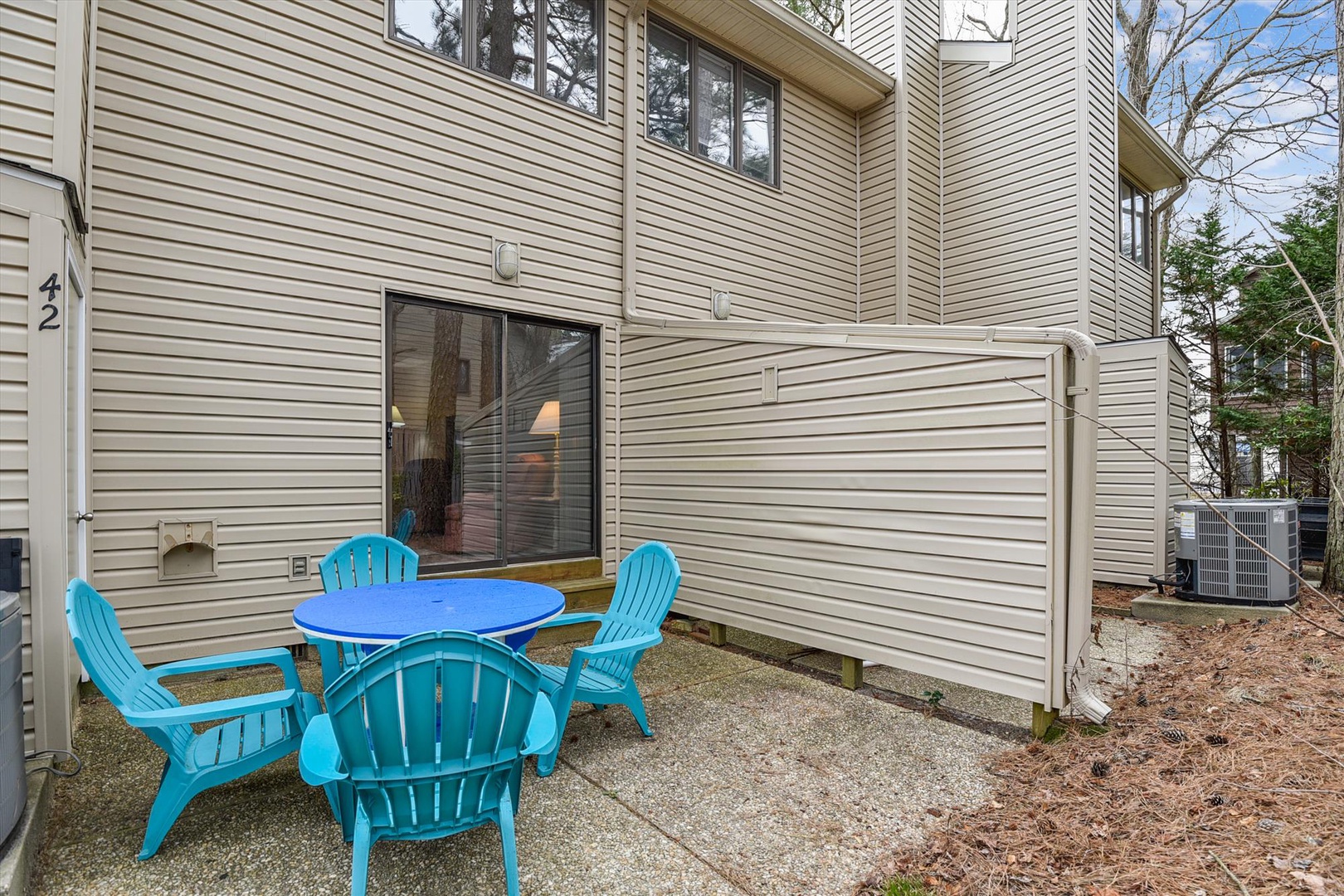 A private outdoor patio area featuring a vibrant turquoise dining set with four Adirondack chairs, offering a cheerful spot for your morning coffee or evening gatherings.