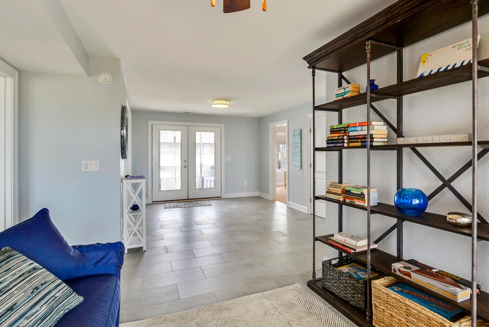 Step into your bright and airy entryway with ample space to settle in. Natural light pours through the French doors, and a curated bookshelf invites you to pick a beach read before heading out to explore.