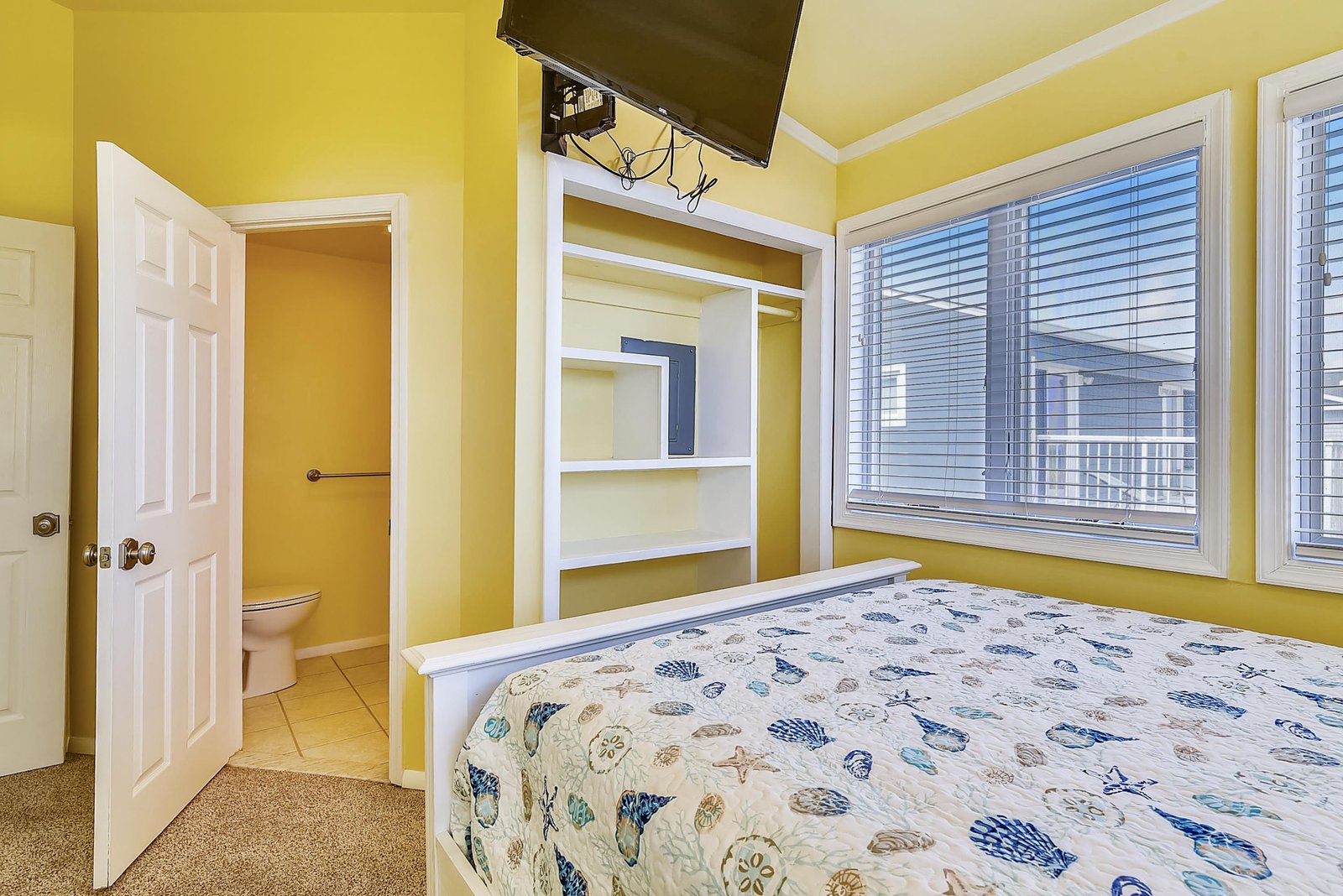 Your cheerful bedroom welcomes you with sunny yellow walls, built-in shelving for your belongings, and easy access to your private bathroom—a bright, cozy retreat after a day of exploring.