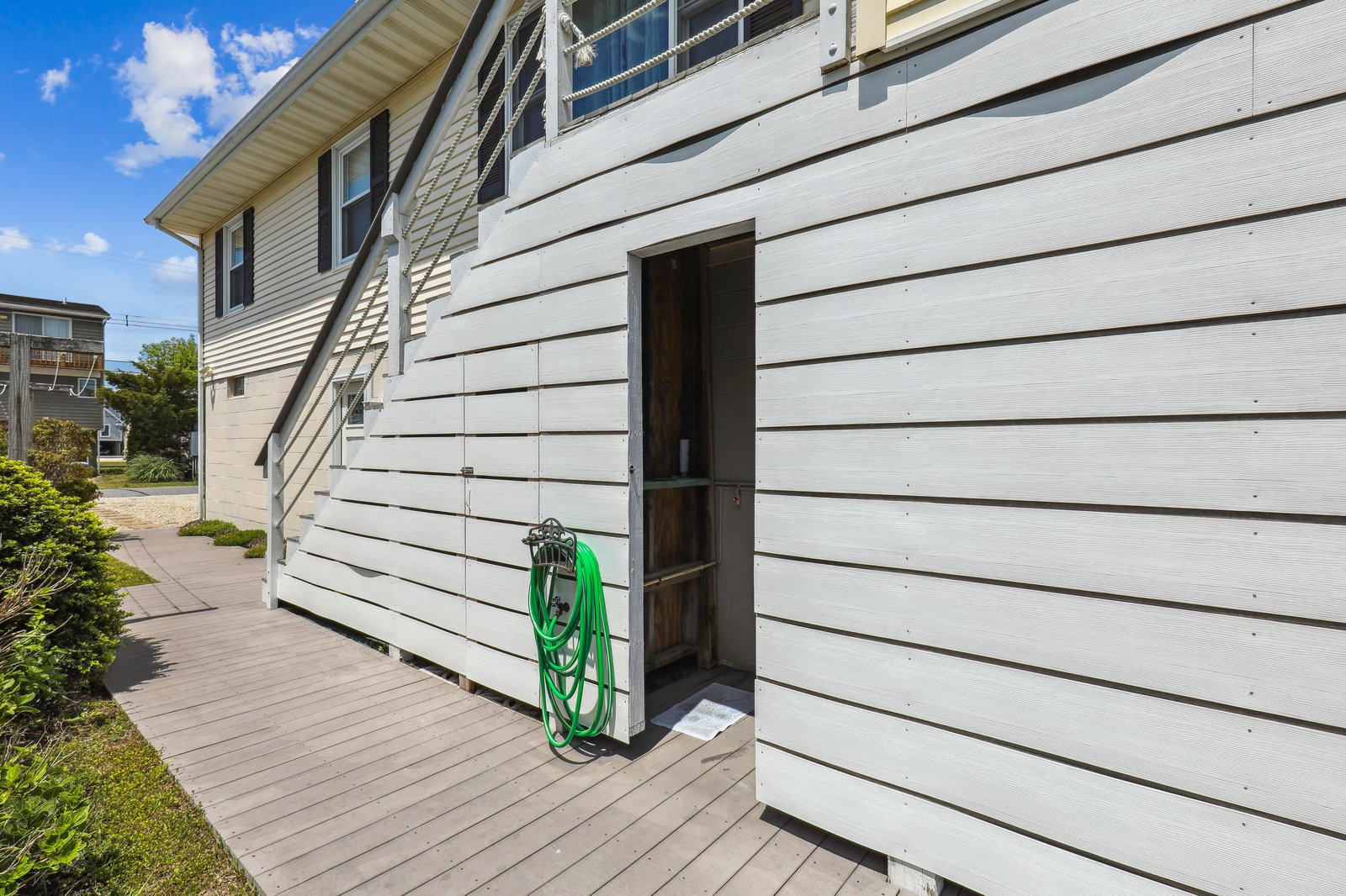 The property features classic white siding and a wraparound deck, offering easy outdoor access under clear blue skies.