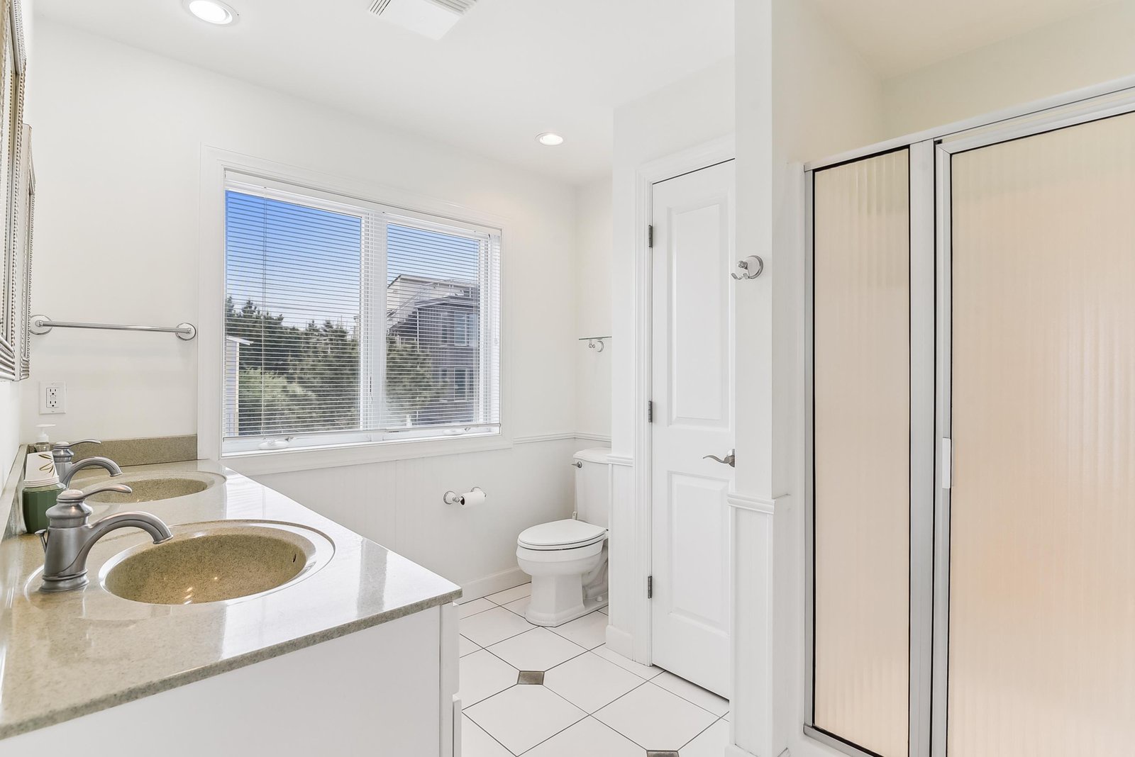 Step into your bright, spotless bathroom with dual sinks and a sleek walk-in shower. Natural light spills through the window, making mornings feel fresh and easy.