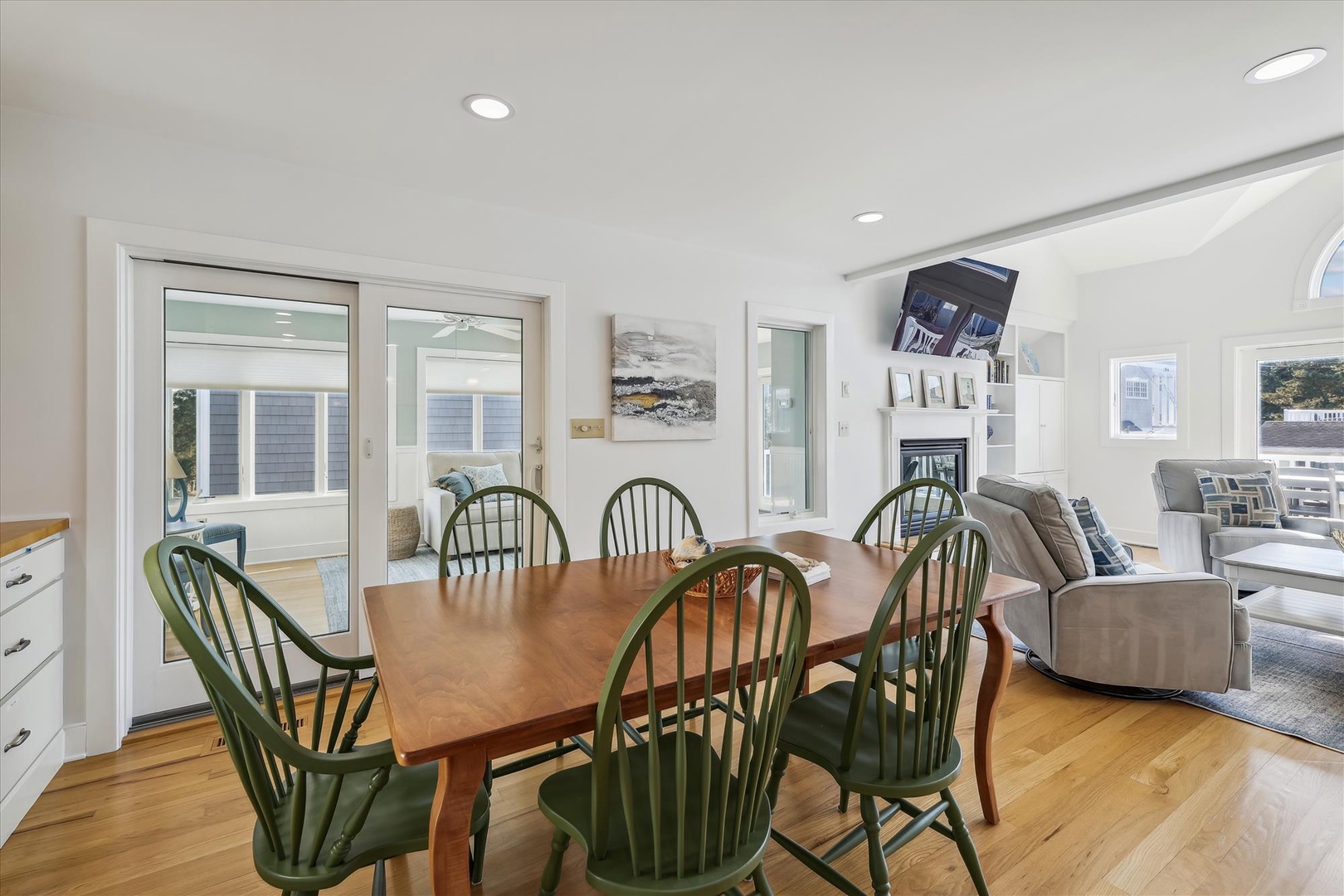 Gather around the warm wood table for meals and laughter, with natural light streaming through windows. Your open-plan living flows seamlessly into cozy lounging spaces beyond.