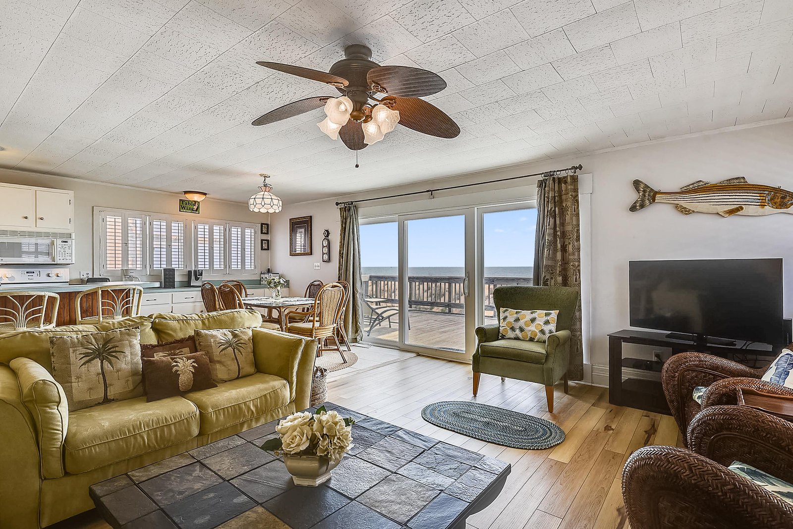 Picture yourself lounging here with ocean breezes drifting in—this bright, coastal-inspired living room invites you to unwind while soaking in stunning sea views through the wall of glass doors.