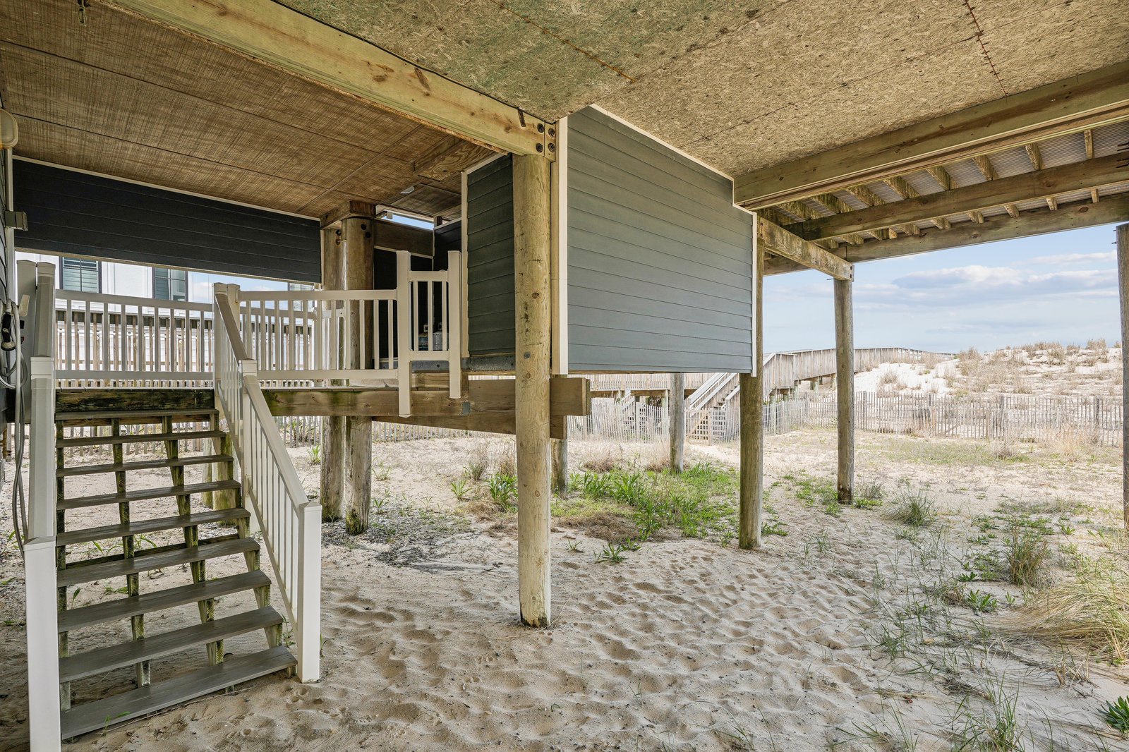 The property sits directly on the sandy beachfront, with an elevated structure providing covered parking and storage beneath the main living area.