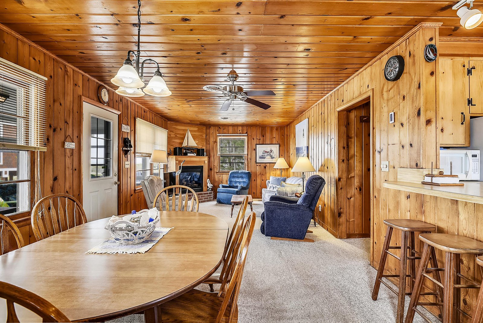 Relax in this cozy cabin with warm knotty pine walls, a dining table for gathering, and a comfortable living area perfect for unwinding after your adventures.