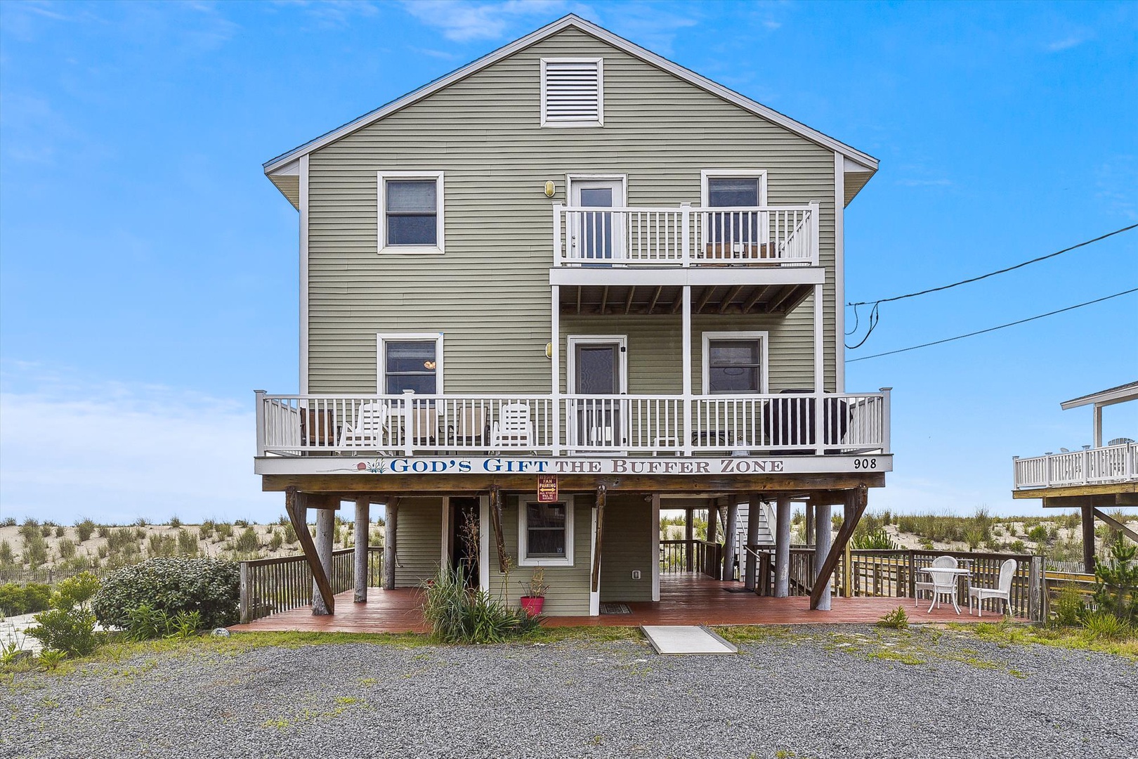 Beach house exterior on stilts featuring multiple levels with private balconies and coastal architecture in a quiet residential area.