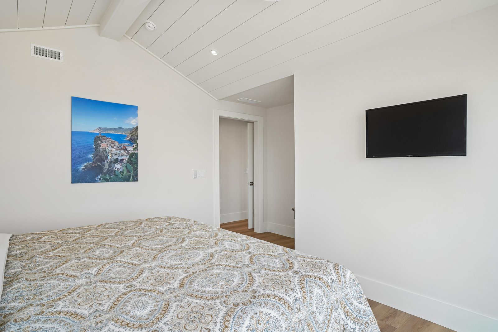 Drift off under vaulted wood ceilings in this serene bedroom, where crisp white walls and warm wood floors create a peaceful retreat for restful nights.