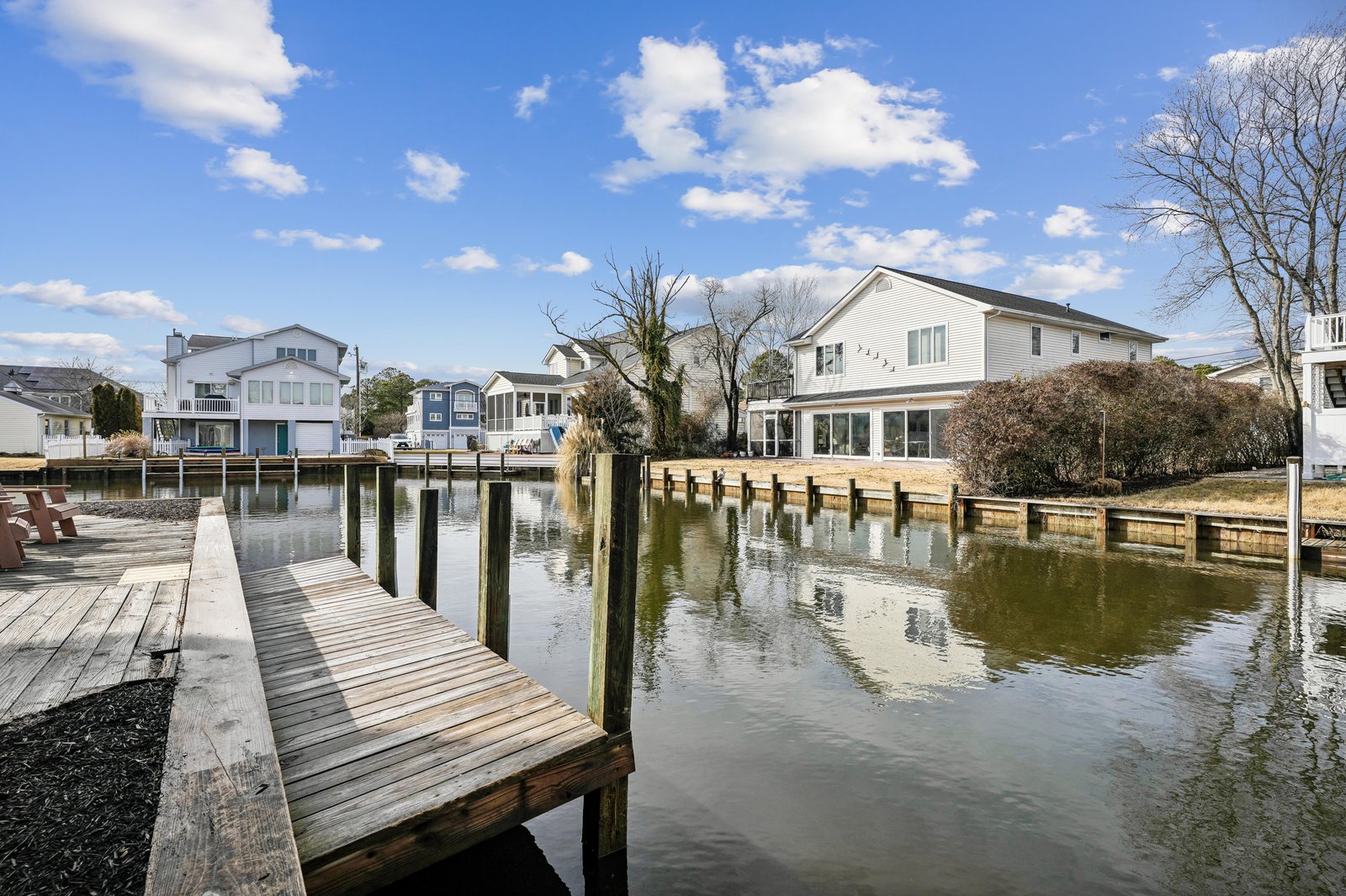 A waterfront property featuring a private dock on a calm canal, surrounded by neighboring homes in a peaceful residential setting.