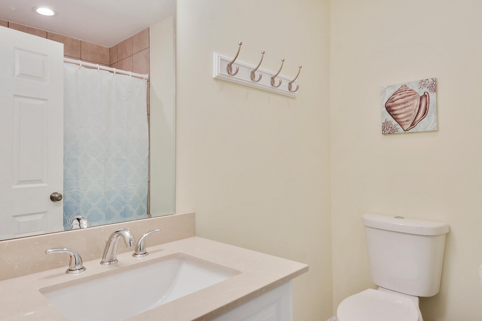 Your private bathroom features a clean vanity, convenient coat hooks, and coastal-inspired touches that bring a relaxed, beachy vibe to your daily routine.