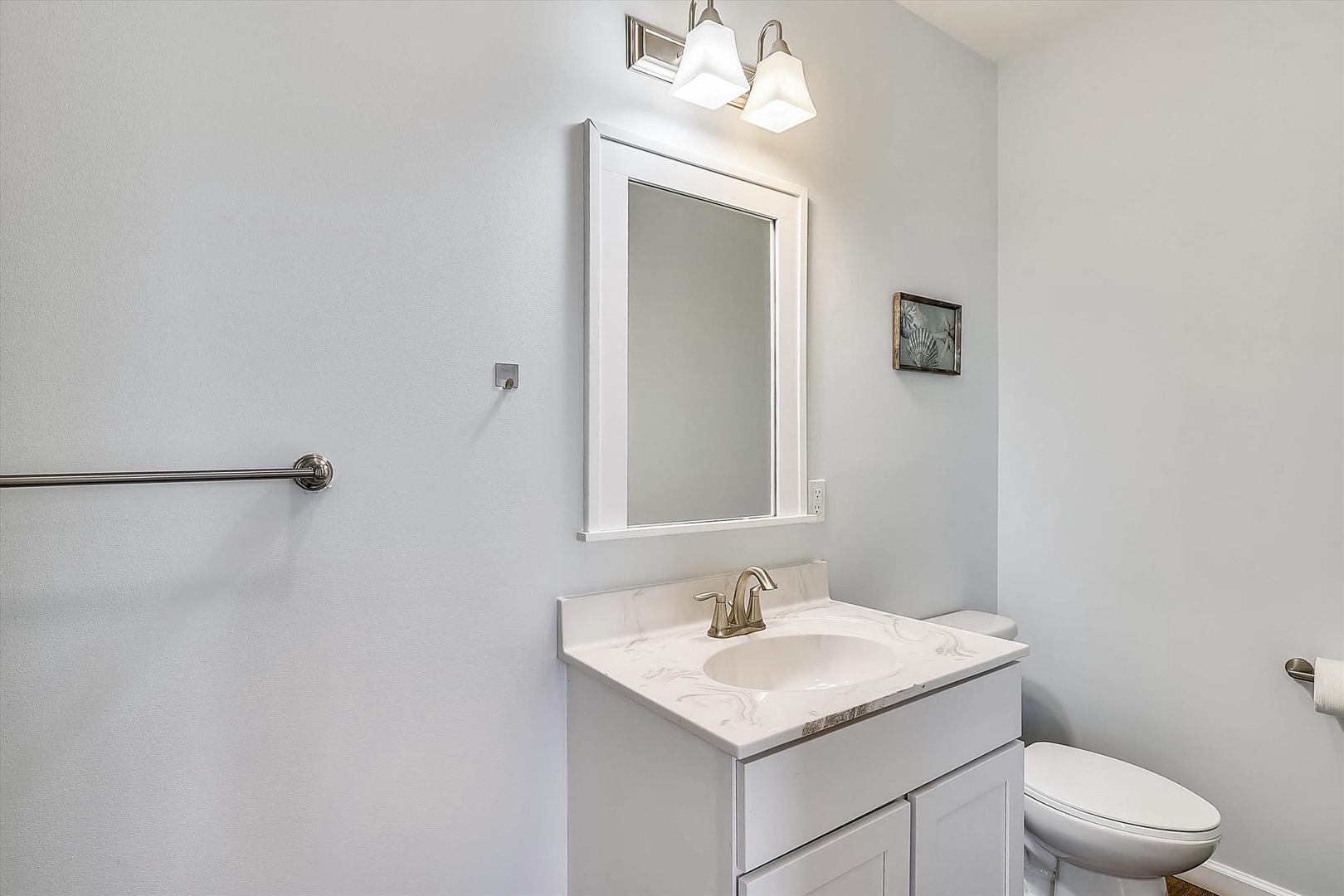 Your private bathroom offers a clean, modern space with marble countertops, bright lighting, and thoughtful touches like a grab bar for added safety and comfort.