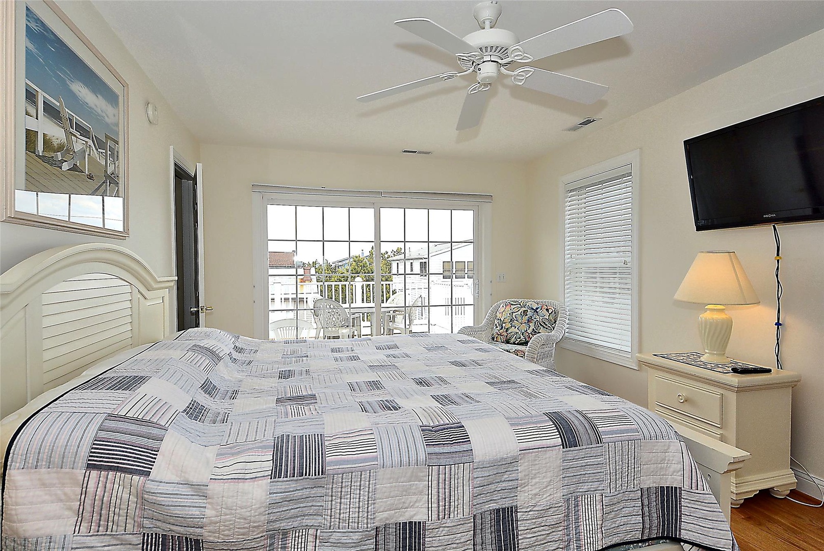 Step into your bright, coastal-style bedroom with a comfy bed, ceiling fan, and balcony doors opening to relaxing views—your perfect retreat.