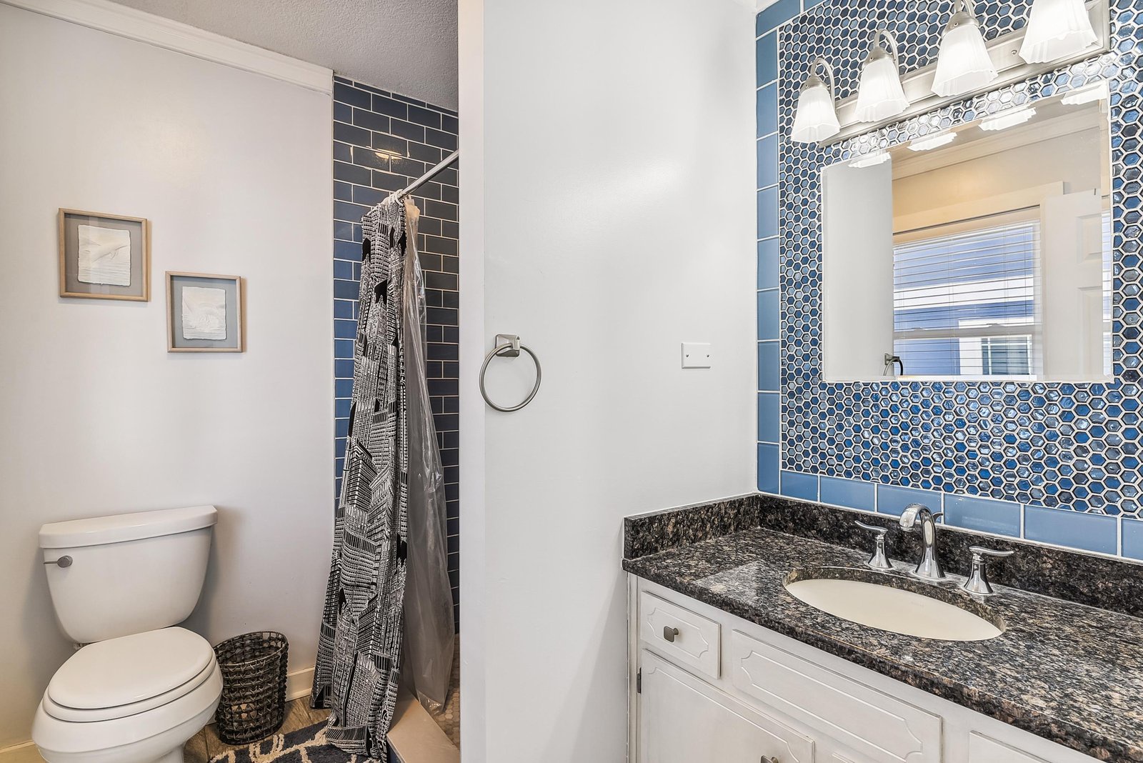 Step into your private bathroom featuring blue hexagon-tiled accents and a sleek granite vanity. Natural light filters through the window, highlighting the modern finishes and thoughtful details.