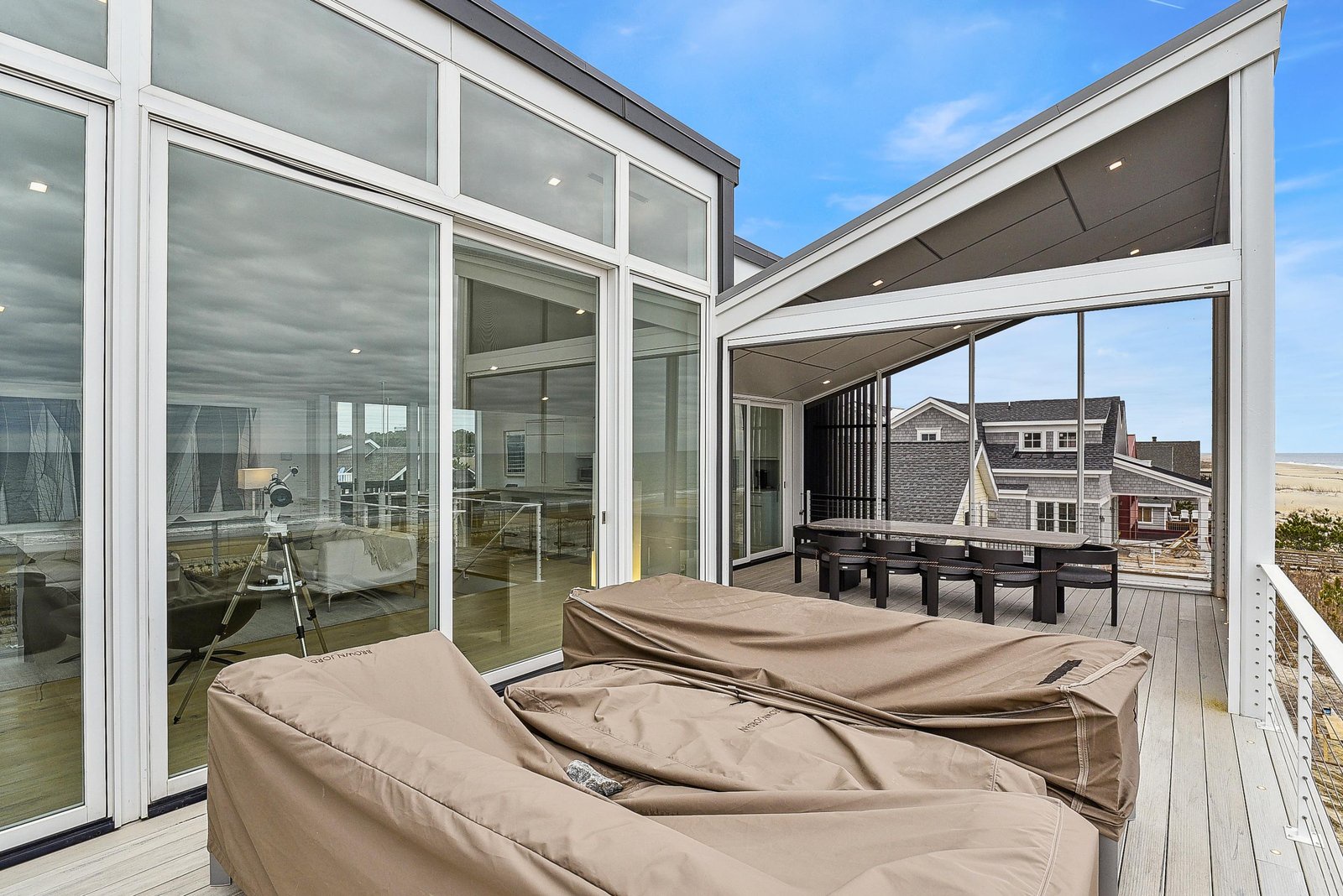 The spacious deck offers stunning views of the coastline and neighboring architecture, perfect for soaking up the sea breeze or enjoying quiet moments under the covered seating area.
