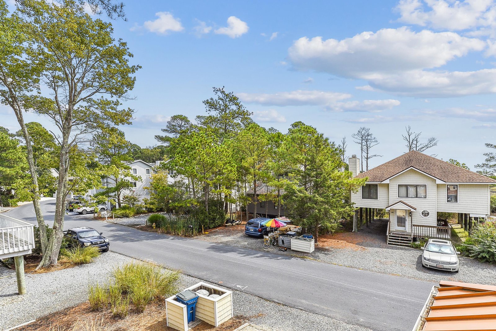Aerial view of the property surrounded by mature trees and peaceful residential streets, with convenient parking on-site.