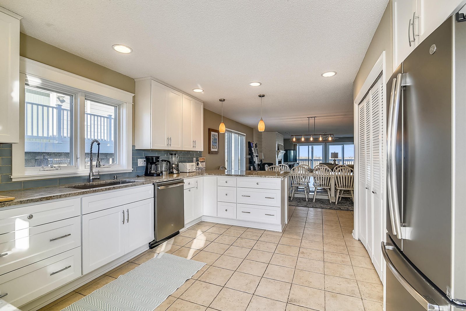 Bright, fully equipped kitchen with granite counters, stainless appliances, and abundant storage. Sunlight streams through windows, and the open layout flows seamlessly into the dining area.