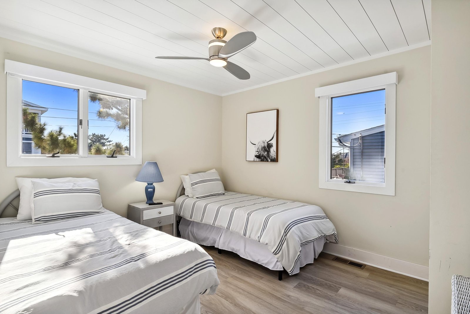 Drift off to sleep in this serene coastal bedroom, where crisp linens and nautical-striped bedding invite your most restful nights under a softly whirring ceiling fan.