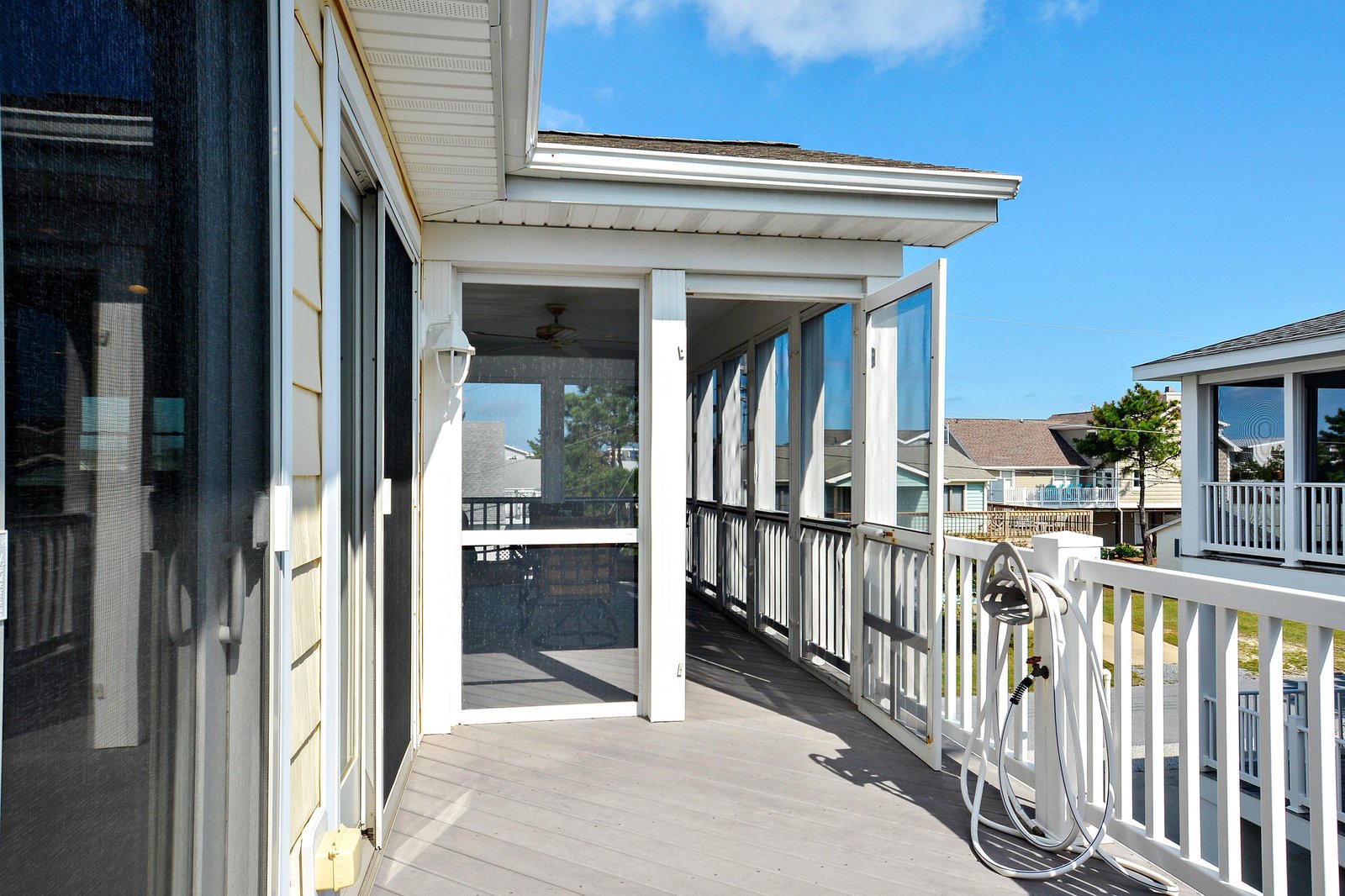 A bright coastal balcony with crisp white railings and beachy vibes, part of your rental home in this relaxed neighborhood.