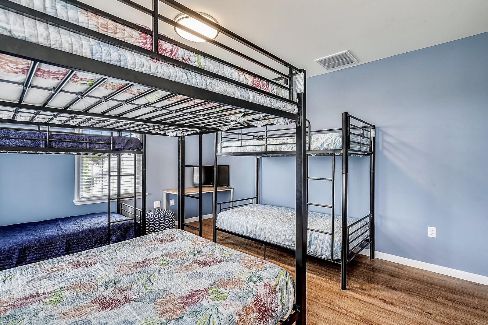Sleeps a crowd with comfort. Multiple bunk beds fill this cheerful room with soft linens, warm wood floors, and peaceful blue walls—perfect for families or friends traveling together.
