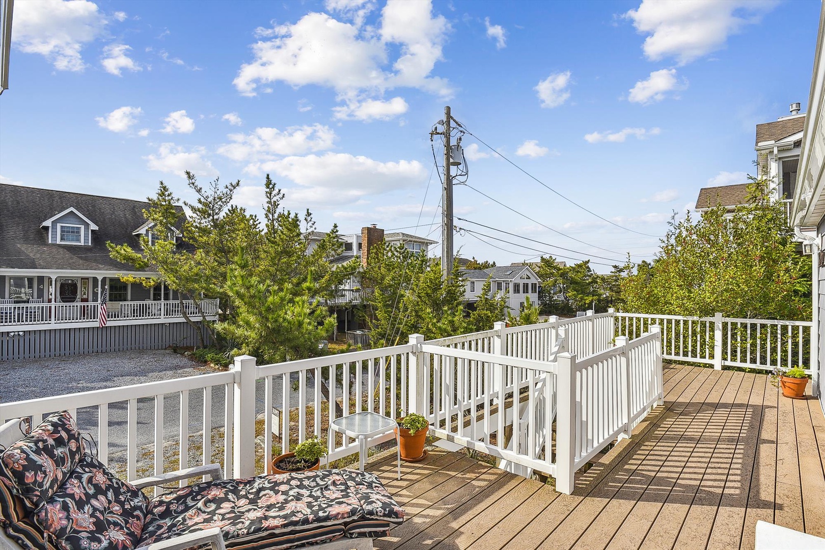 A spacious deck overlooks a quiet residential neighborhood with coastal charm. Sunny skies and fresh air create the perfect setting for your morning coffee or evening relaxation.