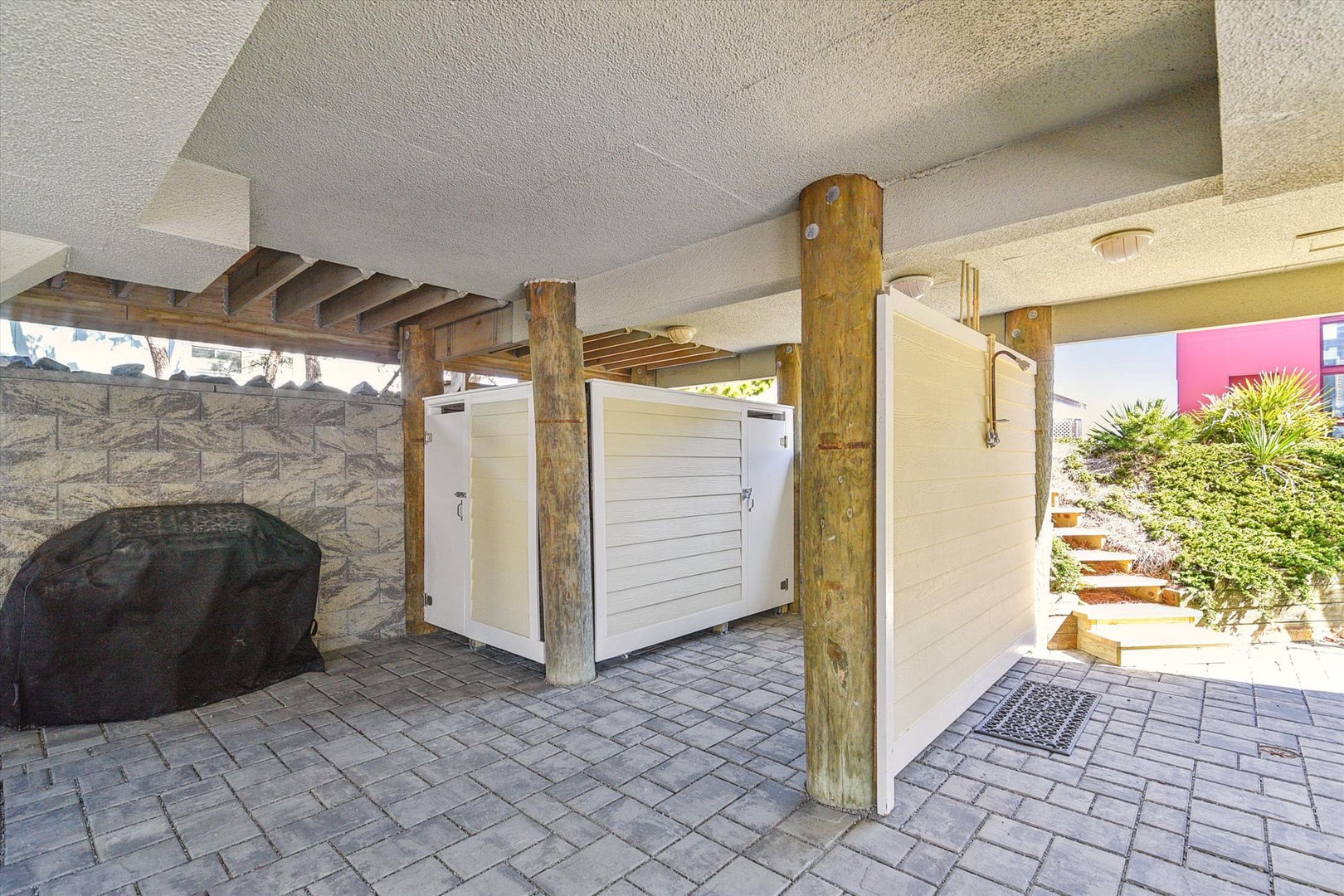 A covered entryway featuring rustic wooden beams, stone accents, and private outdoor shower enclosures with secure storage lockers.
