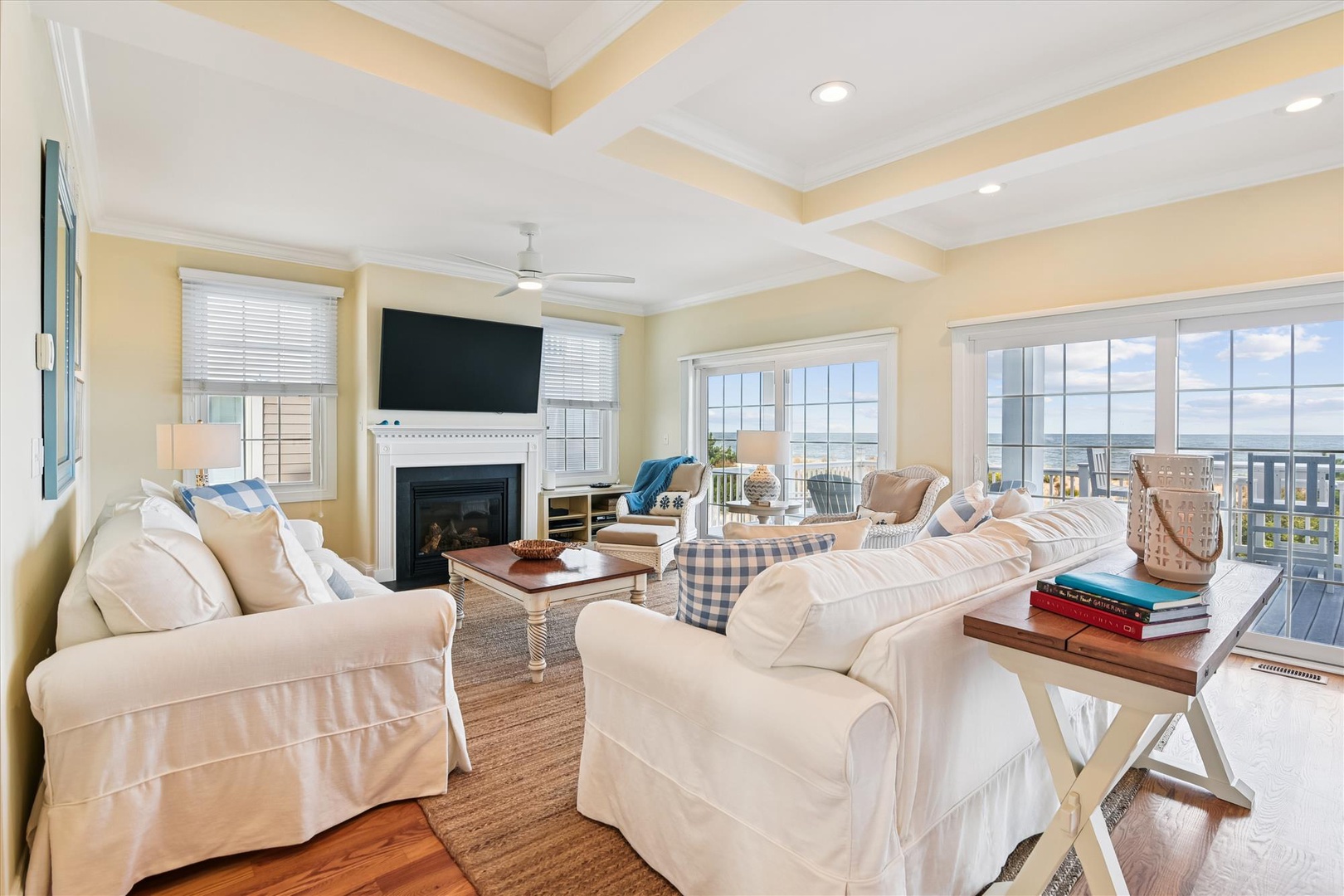 You'll love unwinding in this coastal living room, where plush sofas invite you to relax by the fireplace while you gaze at stunning water views through expansive windows.