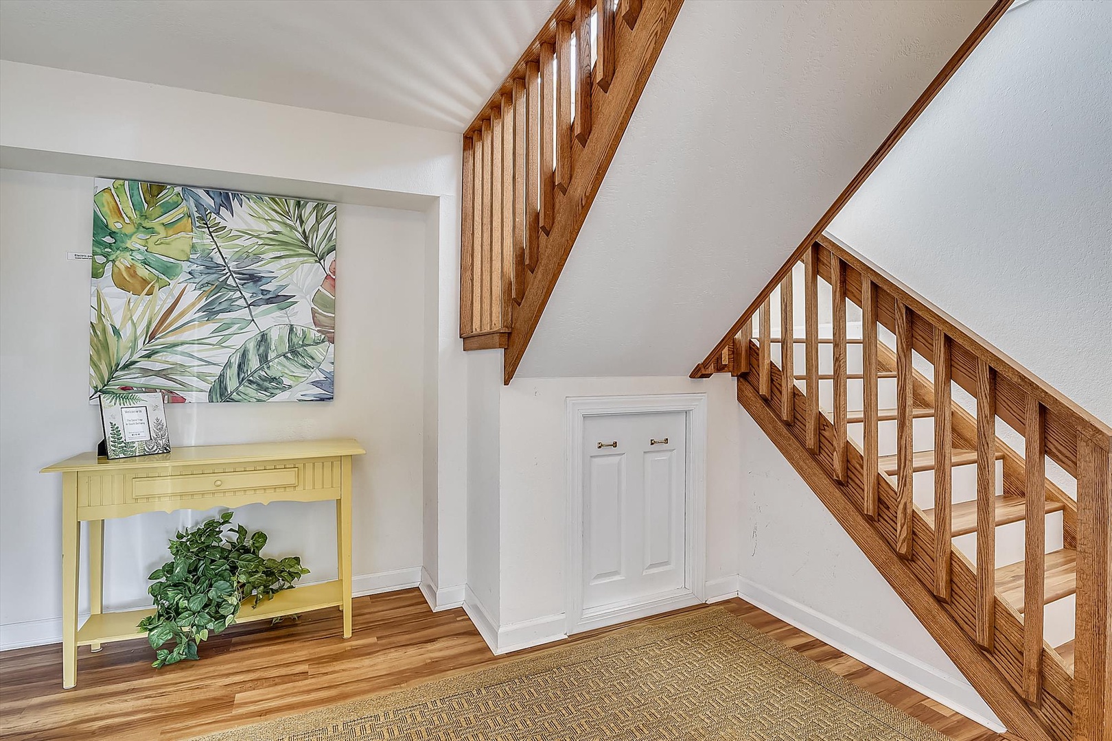 Your charming entryway welcomes you with warm hardwood floors, tropical artwork, and a beautiful wooden staircase leading to your upstairs retreat.