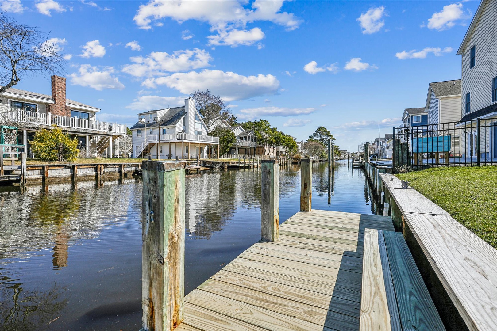 Waterfront community with private docks and boat slips along calm canal waters, surrounded by charming coastal homes.