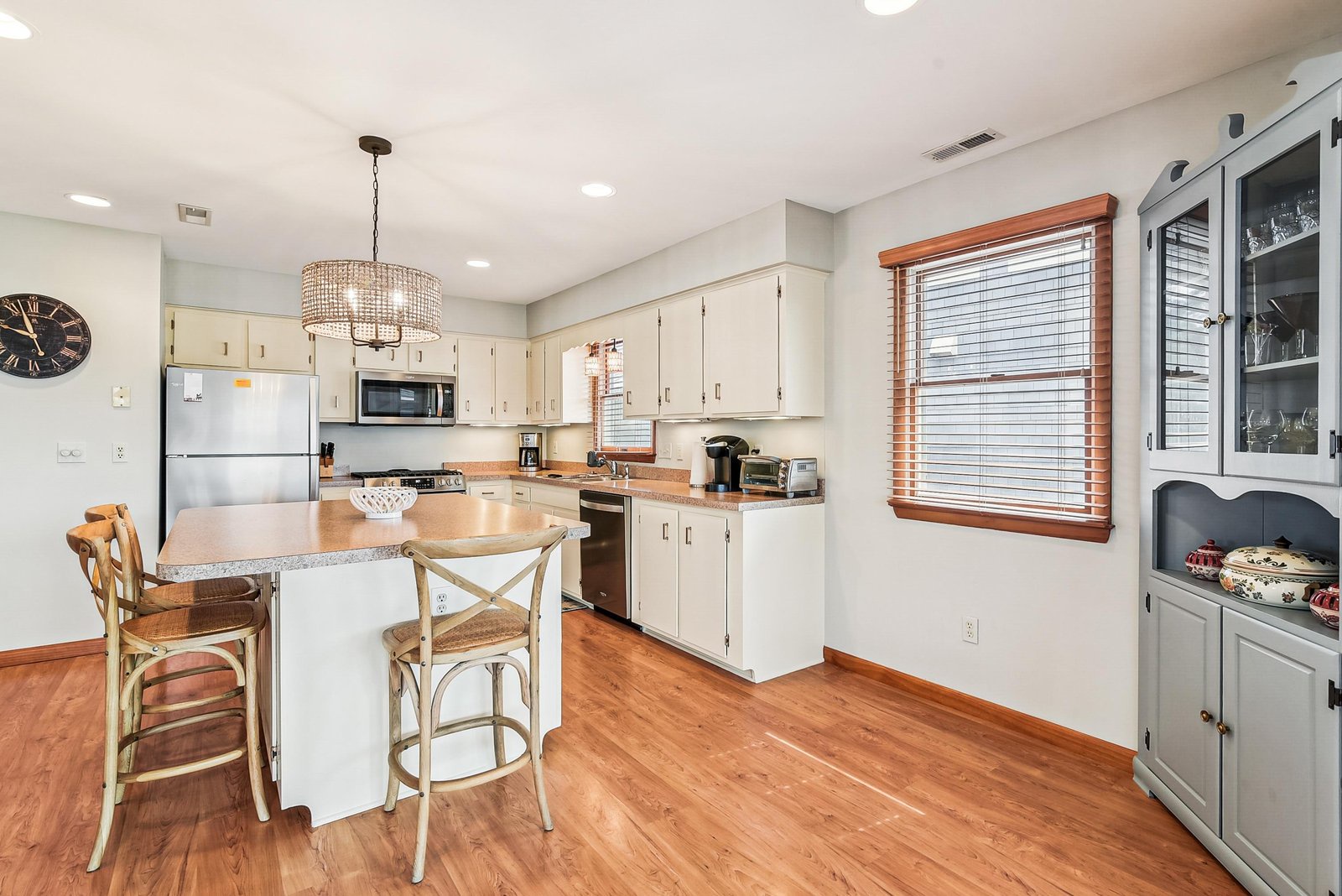 Step into your inviting kitchen, where charm meets function. A cozy island with bar seating, warm wood floors, and a beautiful chandelier make meal prep feel effortless and relaxed.