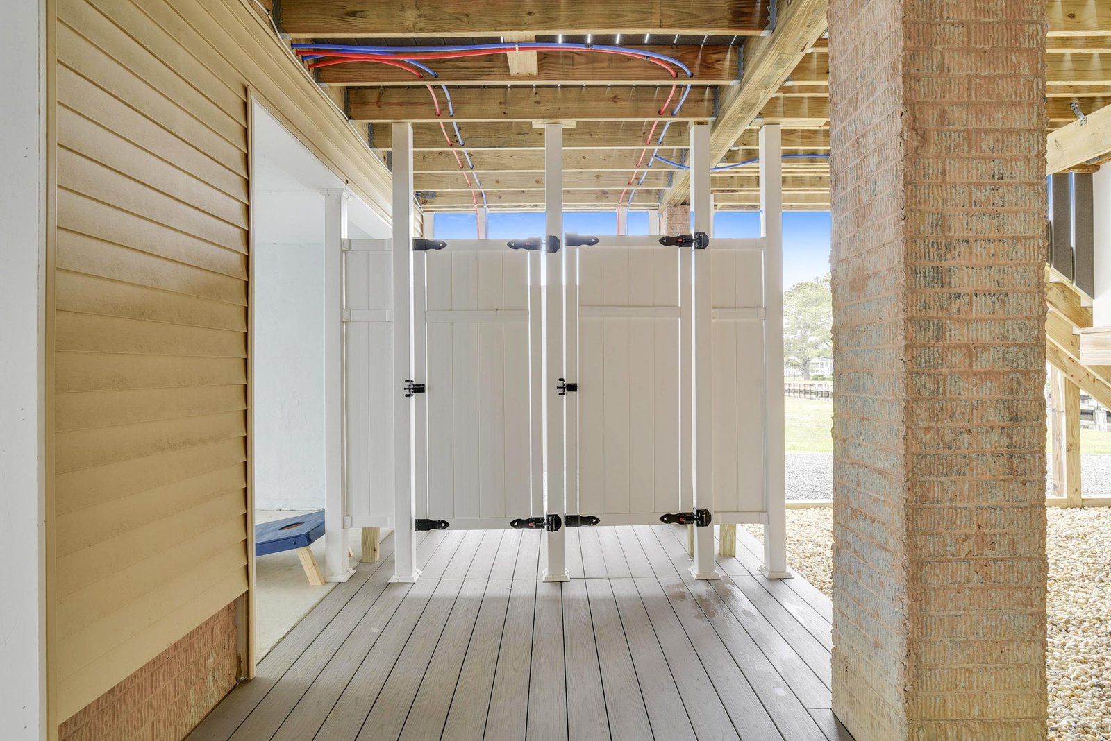 Two private outdoor shower stalls stand ready on the covered deck, framed by natural wood and open to fresh air. The perfect beachside rinse after sandy toes and salty swims.